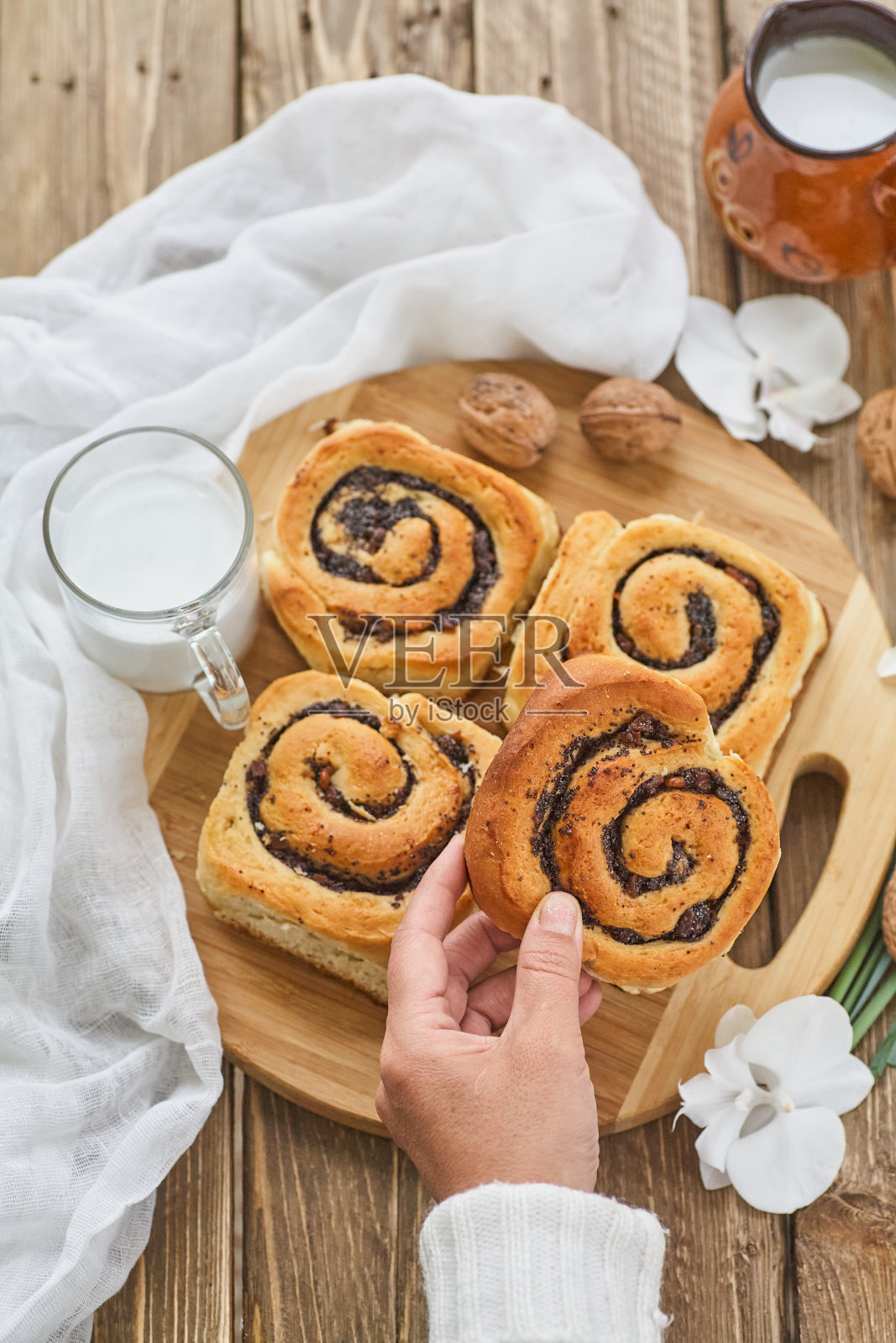 女手里拿着自制的果酱面包，盛在旧木桌上，配着核桃和一杯牛奶照片摄影图片