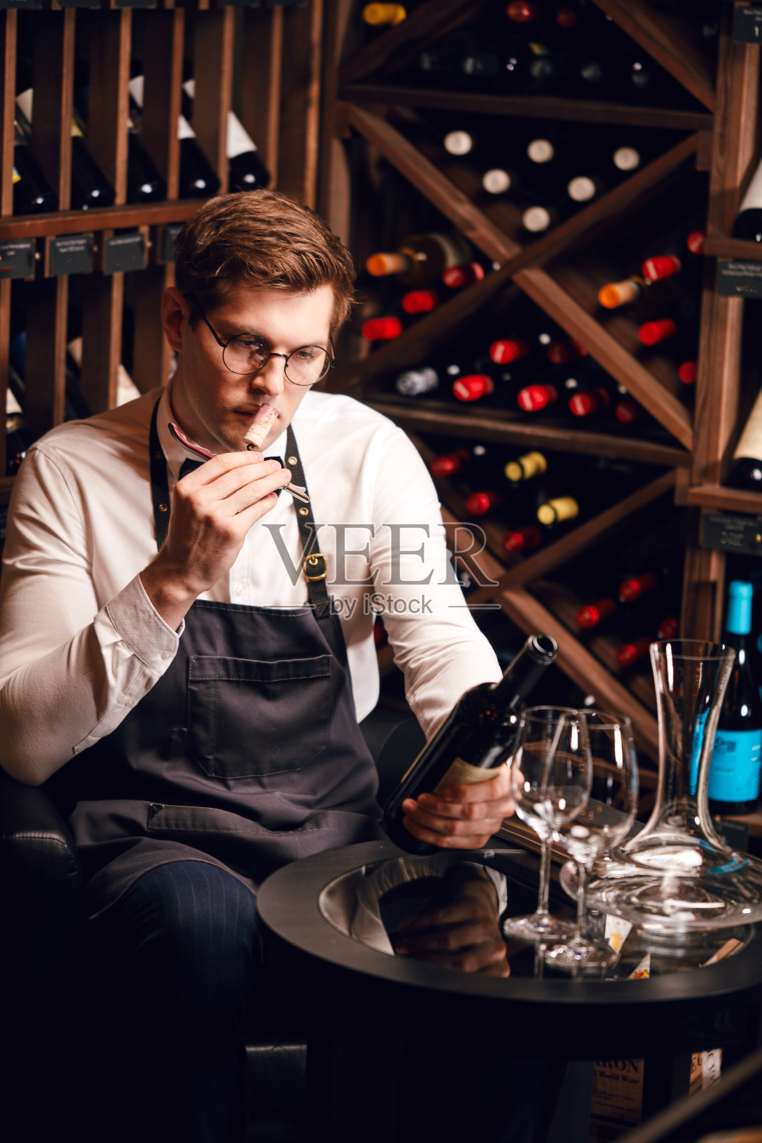 侍酒师在设有酒架的餐厅用开瓶器开酒瓶。照片摄影图片