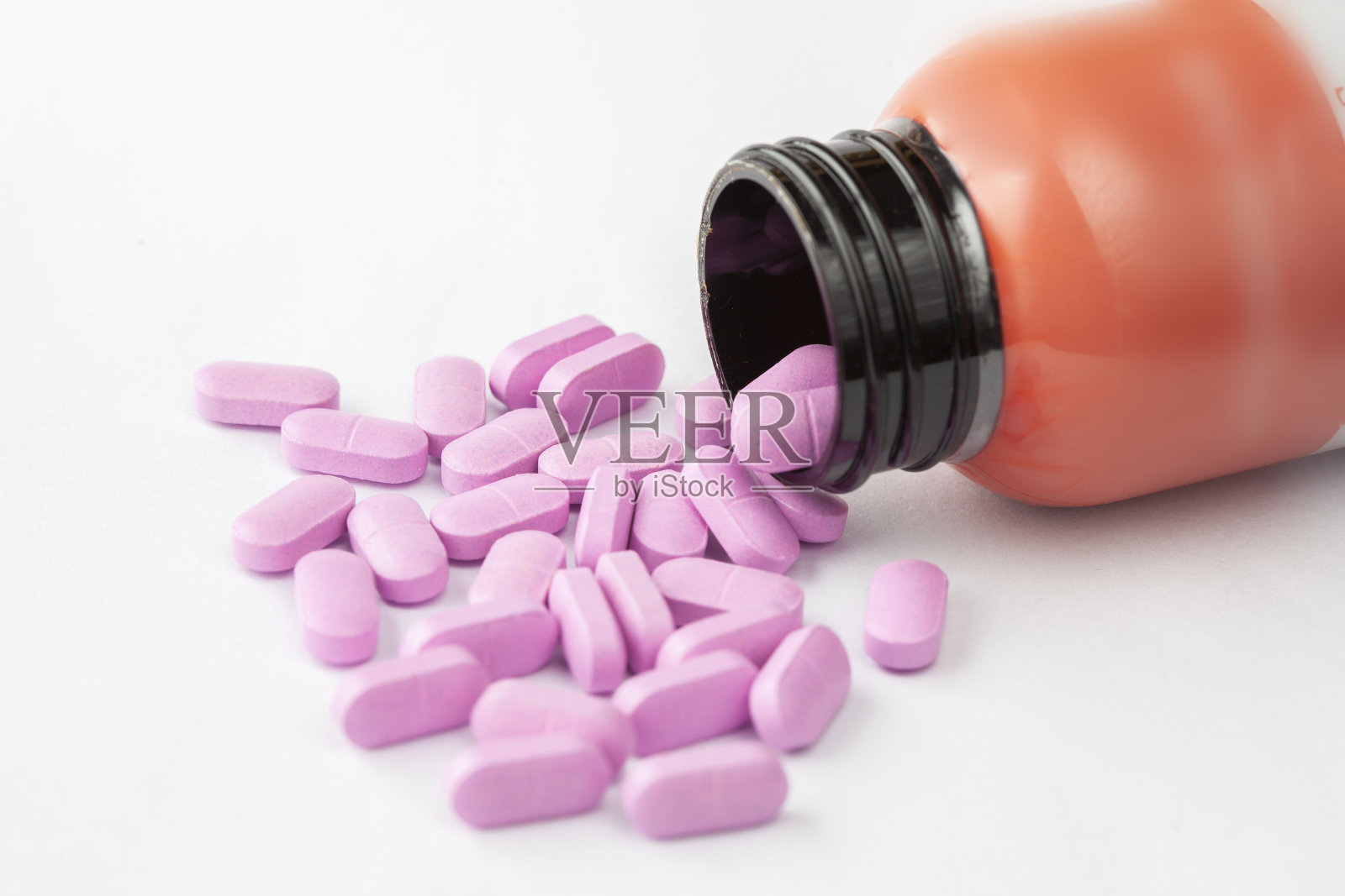 粉红色的药丸从瓶子里溢出来照片摄影图片