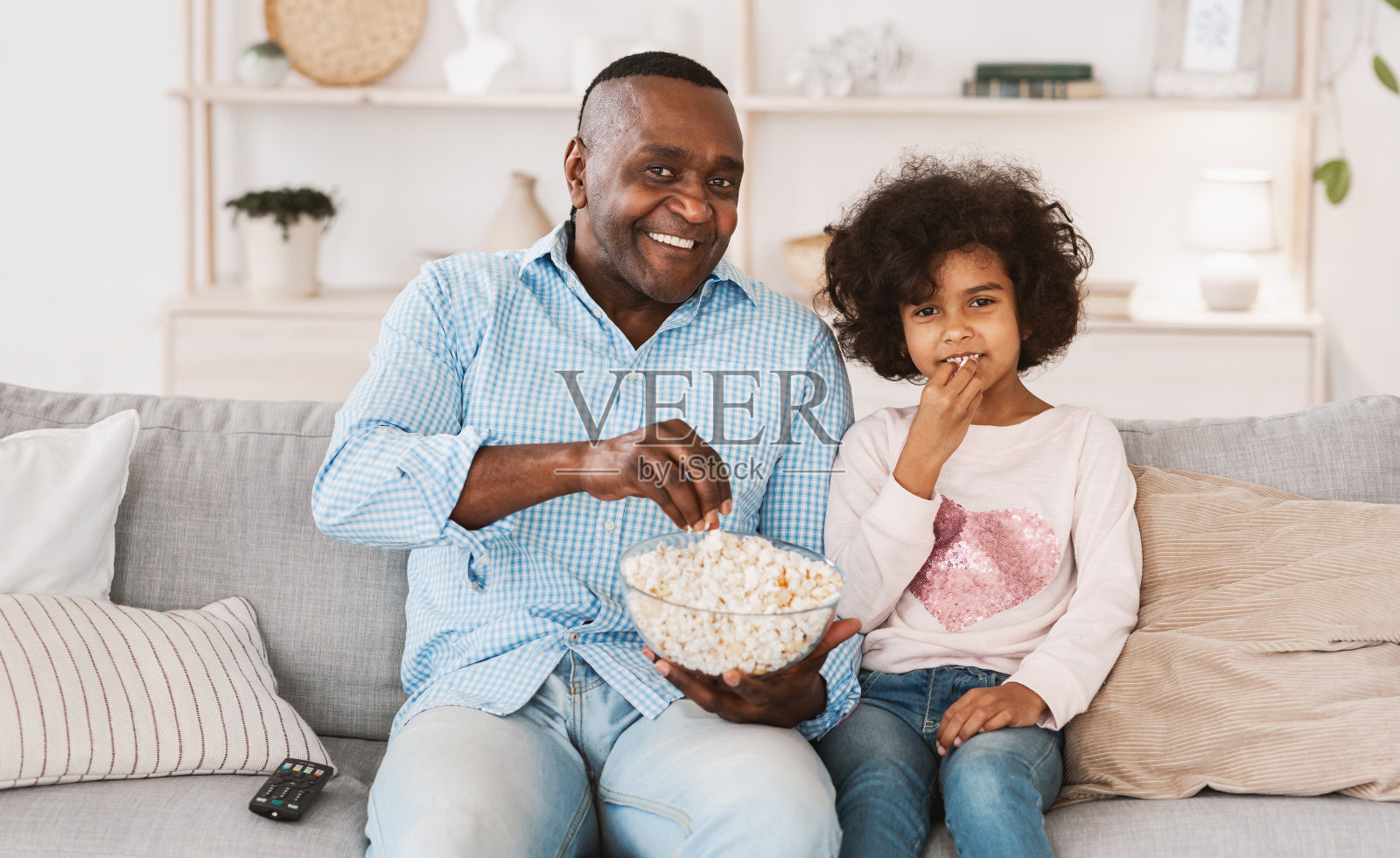 家庭娱乐。快乐的非洲裔美国孩子看电视和爷爷在室内沙发上照片摄影图片