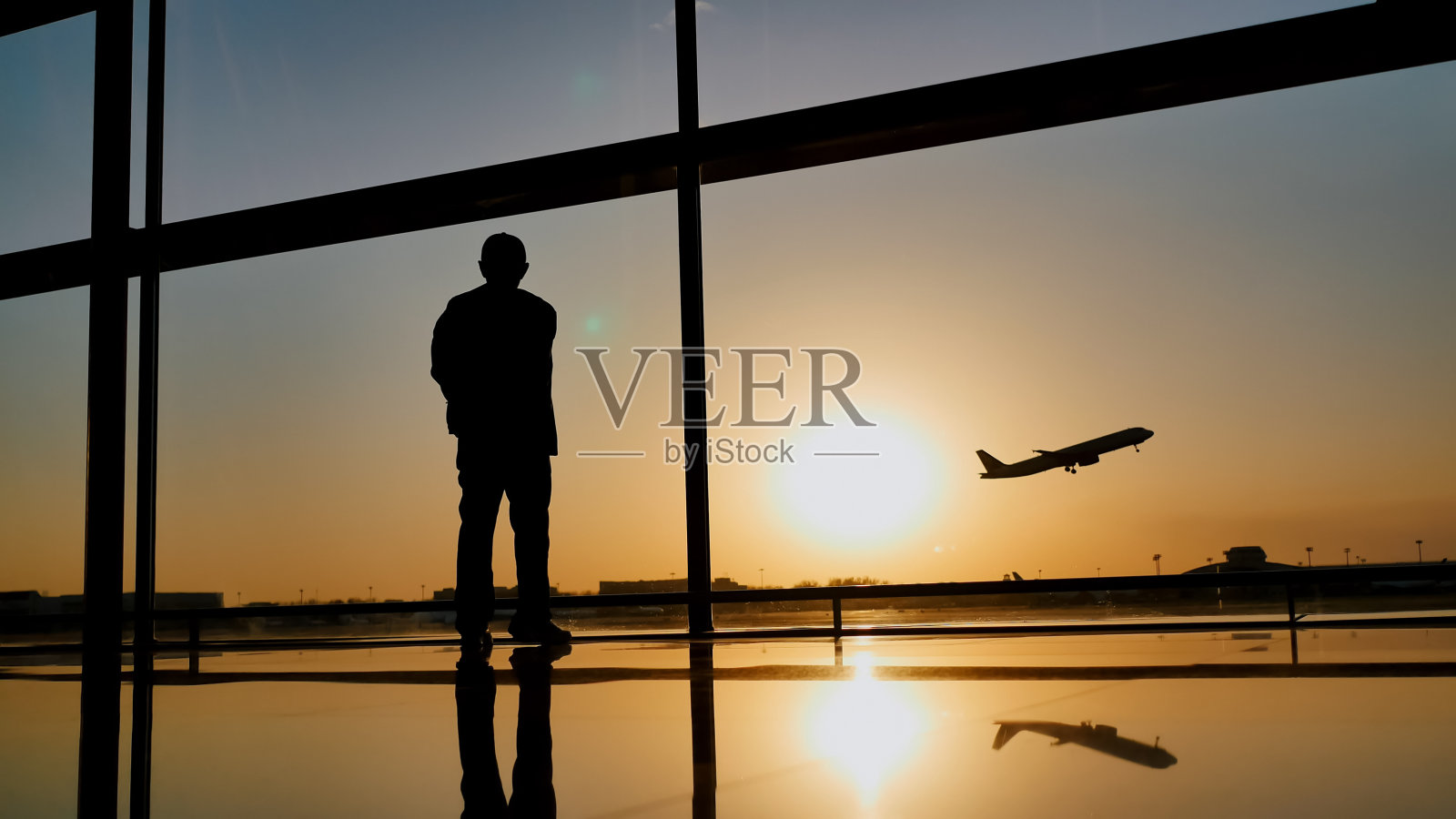 日落时分机场窗口观看飞机起飞的游客剪影照片摄影图片