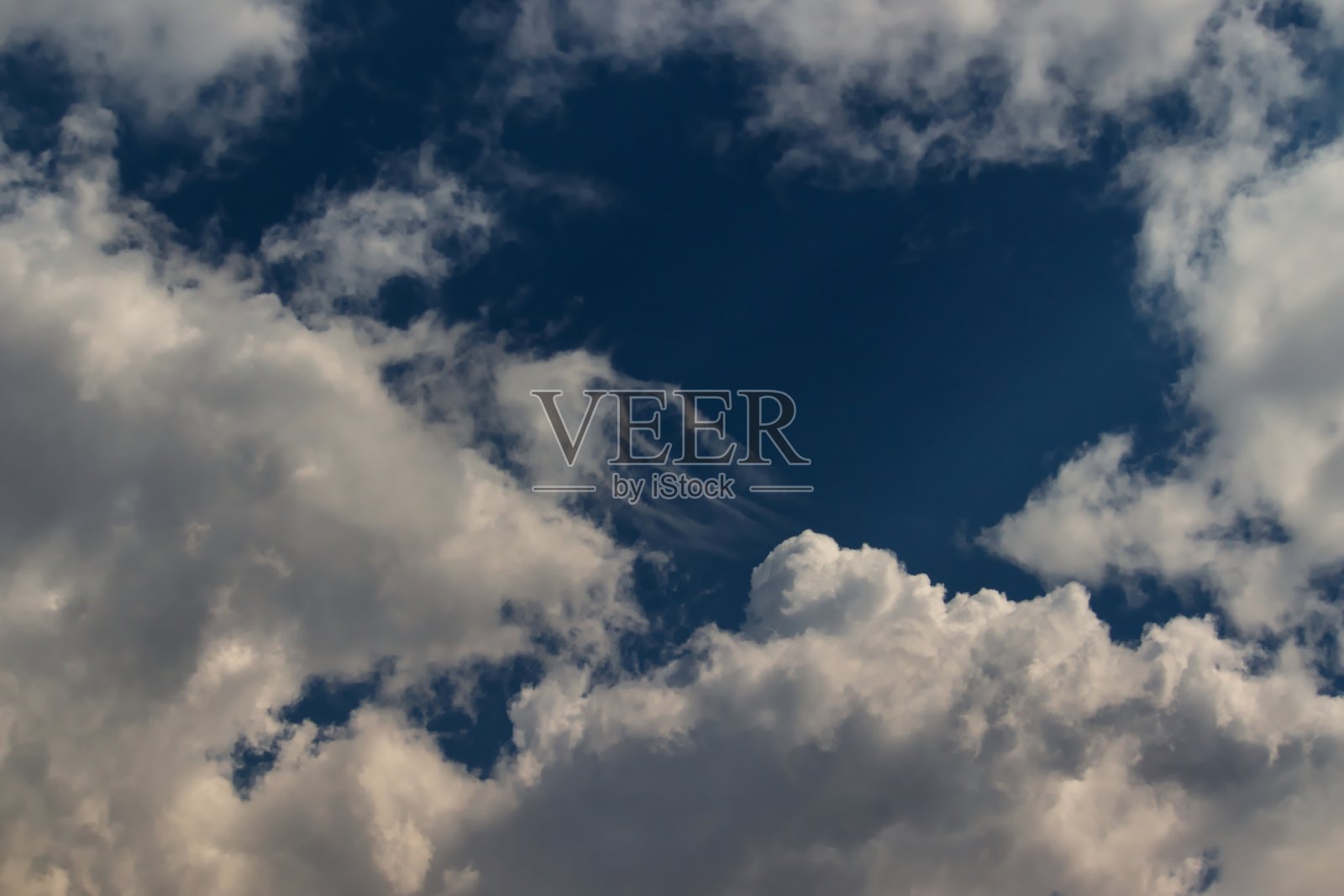 一片蓝天，被奇形怪状的云朵包围着。照片摄影图片