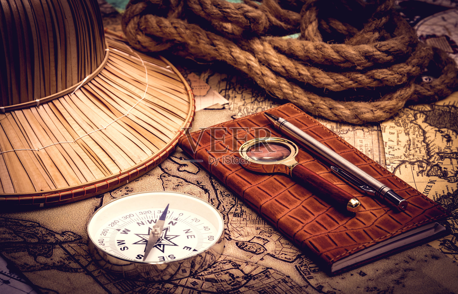 在灯光下，用指南针和放大镜夜视一幅旧地图照片摄影图片