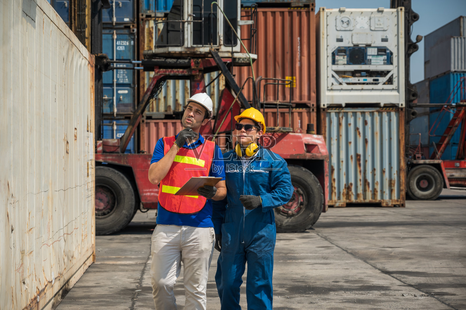 在集装箱码头工作的工头和码头工人拿着剪贴板检查。业务物流进出口航运概念。照片摄影图片