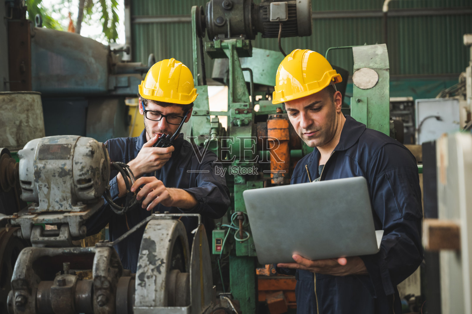 产业工人正在大型工业工厂的许多设备上工作。照片摄影图片