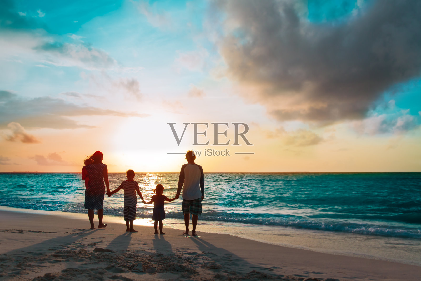 幸福的家庭和树上的孩子们在日落海滩散步照片摄影图片