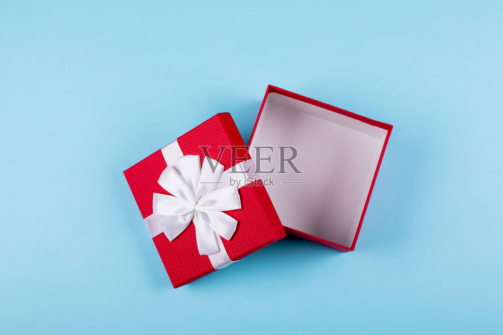 打开红色礼品盒在蓝色纸背景。俯视图，平放，放置物体。模型、节日的概念。照片摄影图片