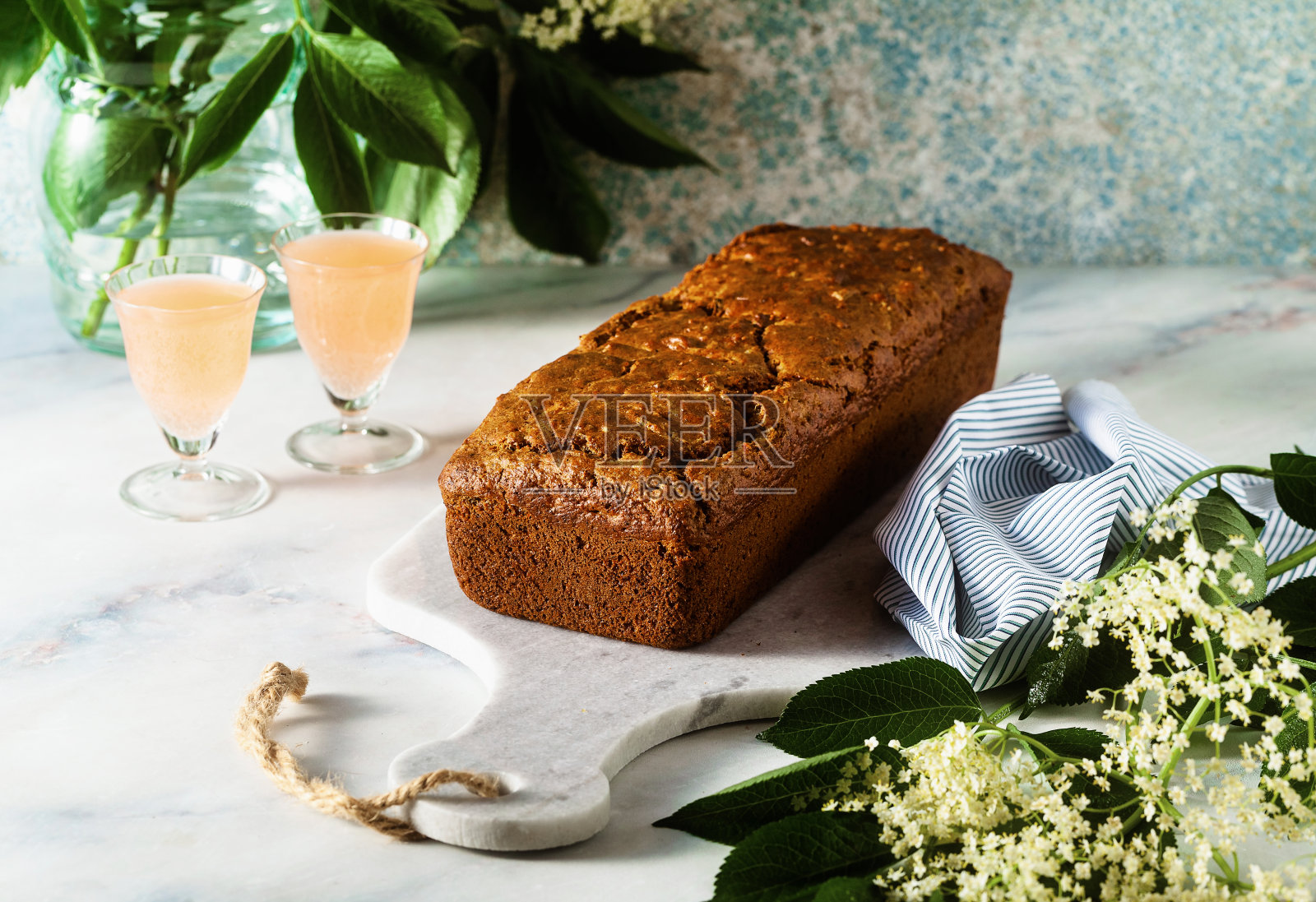 夏日香甜的面包蛋糕摆在桌上，桌上放着鲜花和盛着饮料的玻璃杯。早午餐或早餐的甜点照片摄影图片