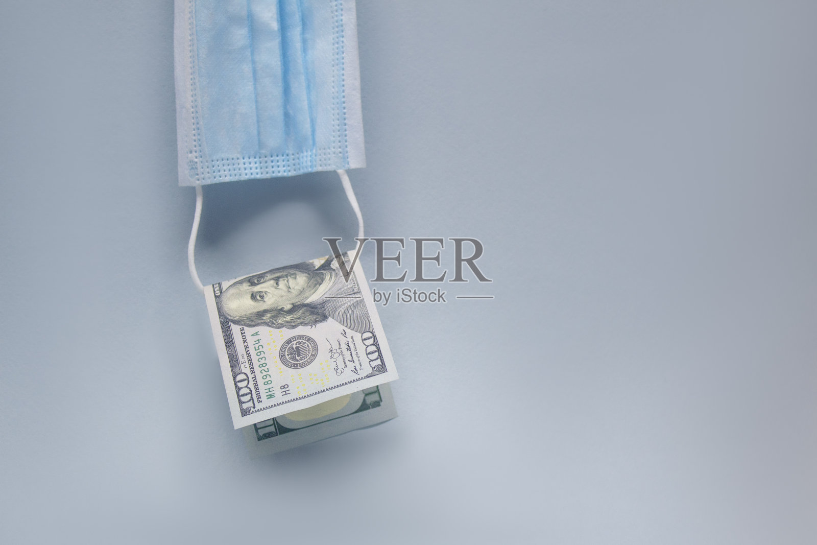 医用口罩和100美元的Covid-19冠状病毒在灯光背景。关于药物主题的库存照片。照片摄影图片