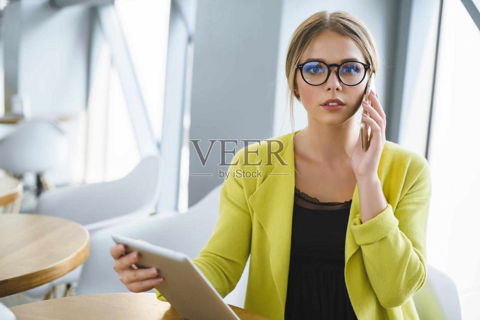 戴眼镜的年轻女商人在咖啡馆的一张桌子旁工作。照片摄影图片