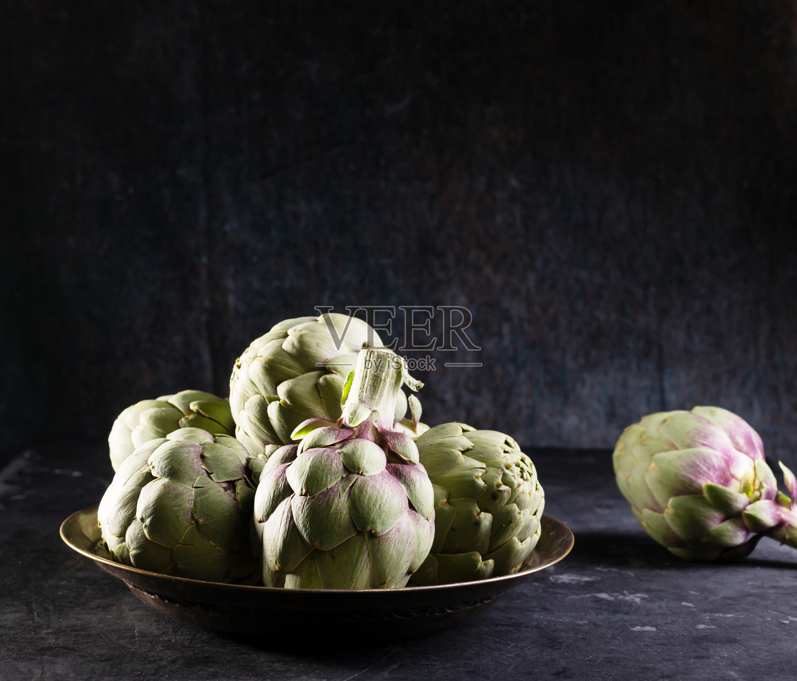 金属盘子上放一堆绿色的西班牙或意大利洋蓟照片摄影图片