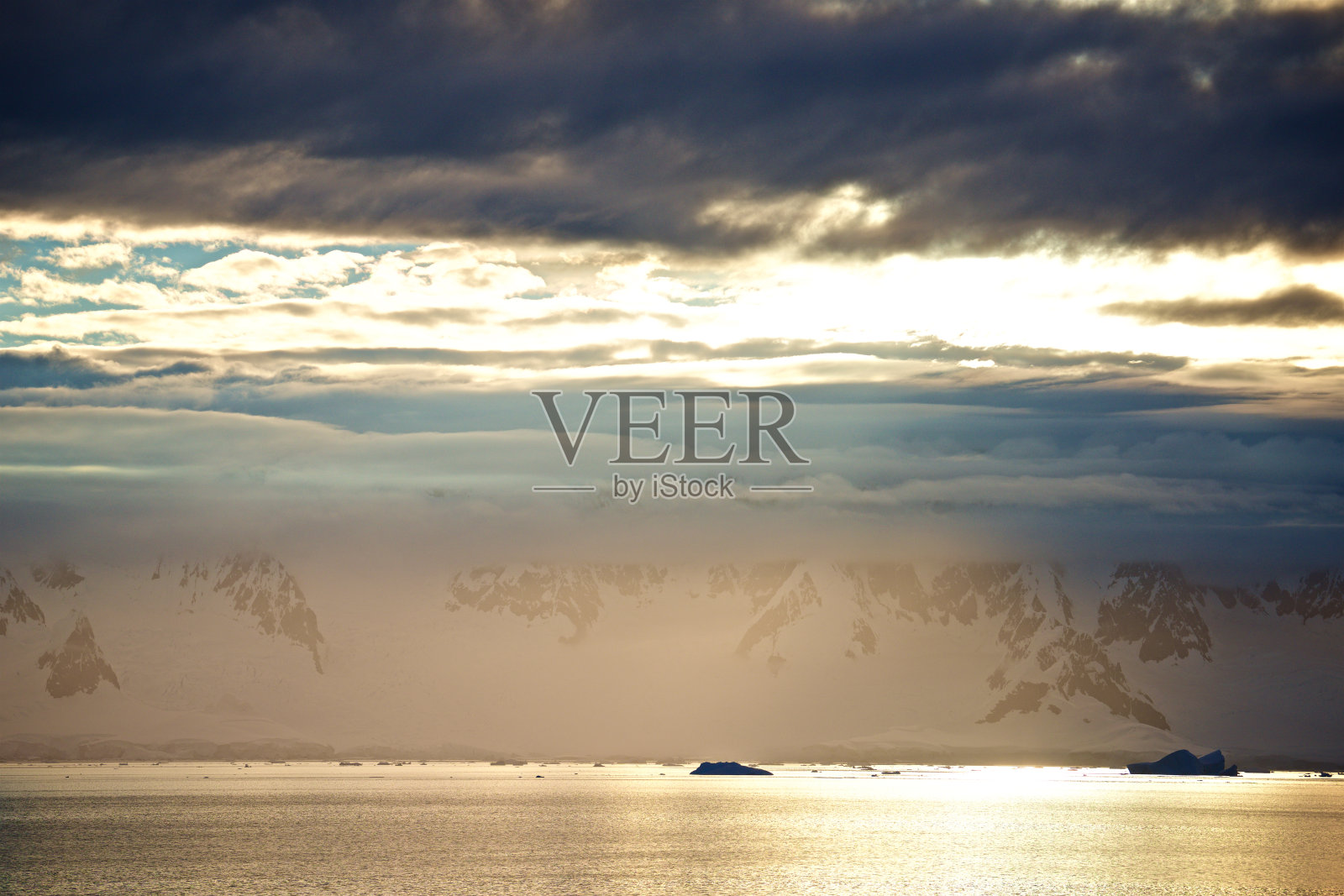 南极半岛雪山和海洋上空的云层间的阳光照片摄影图片