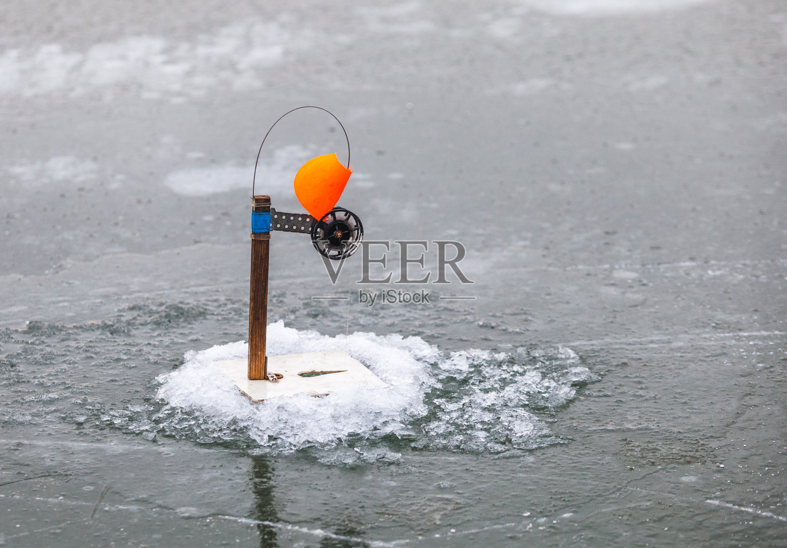 应对旗帜。冬天在结冰的河里钓鱼。照片摄影图片