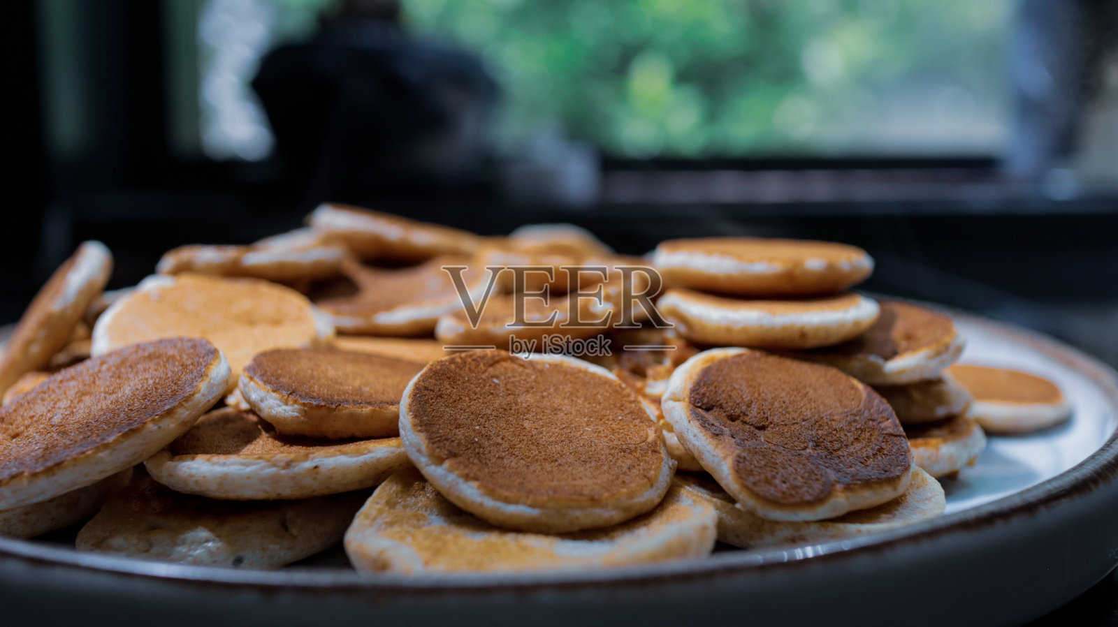 迷你薄烤饼，在蓝色的盘子和黑色的背景照片摄影图片