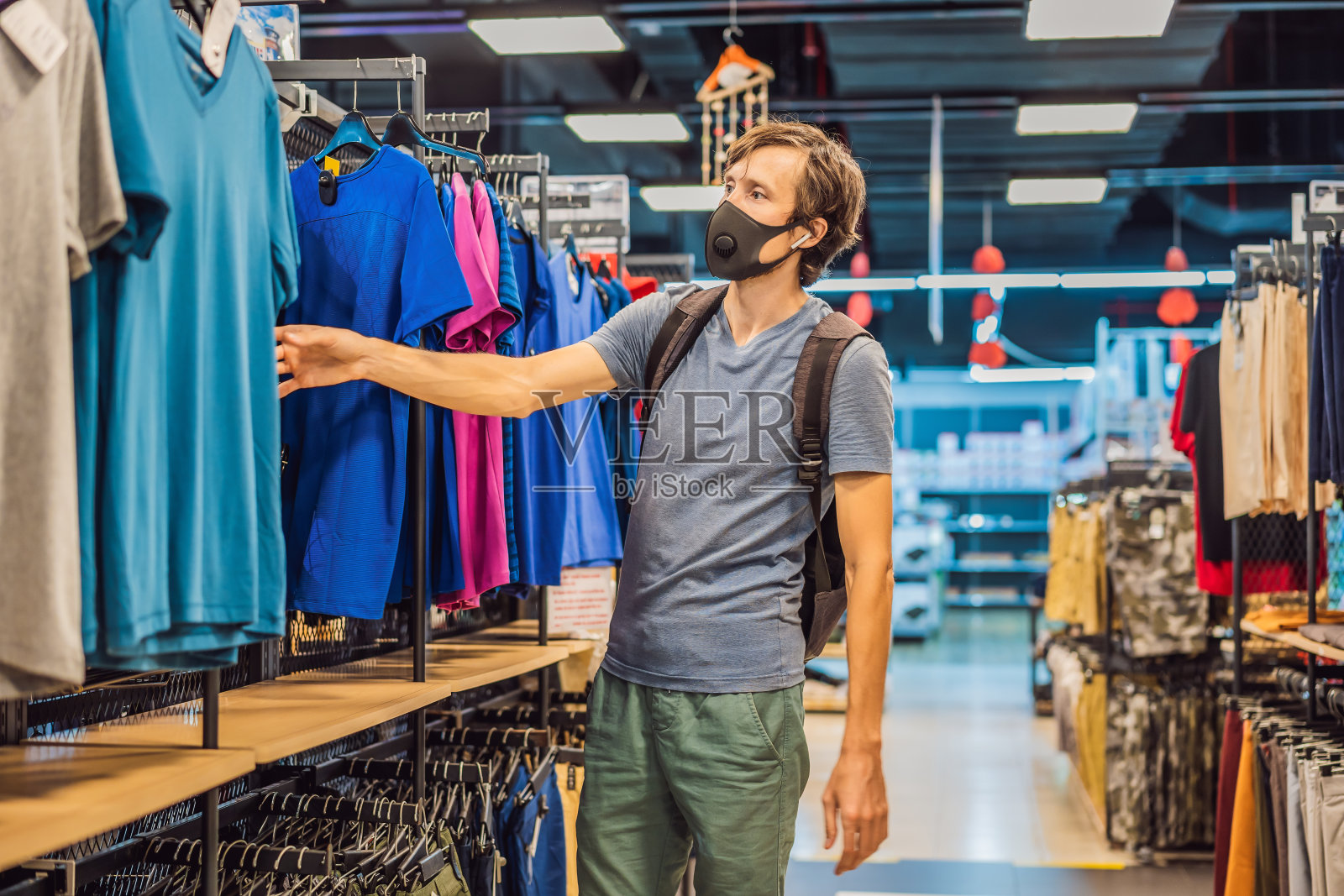 一名男子因为冠状病毒在服装店戴着医用口罩。隔离结束了，现在你可以去服装店了照片摄影图片