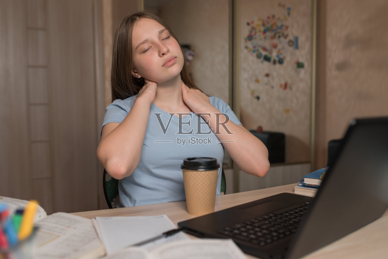 少女十几岁，累揉脖子肌肉，长时间工作又累又累，疲劳嗜睡，在家电子教育笔记本上网。学校教育预备大学。一杯咖啡和茶。照片摄影图片