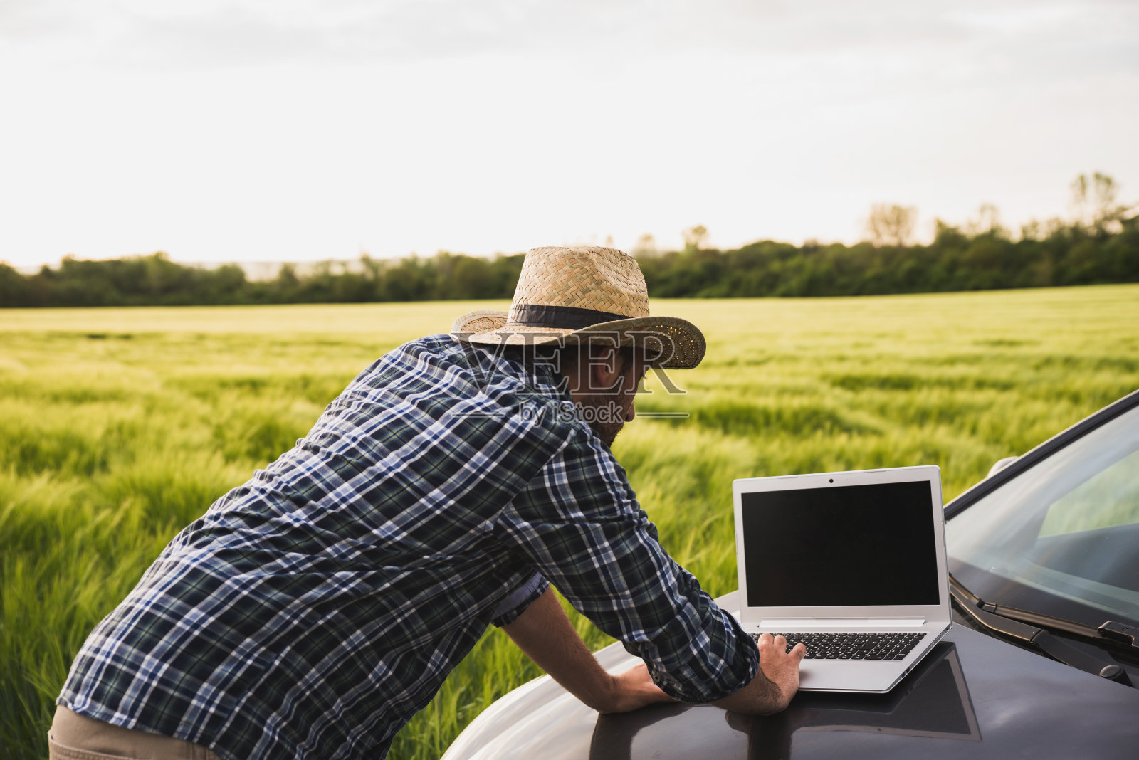 一个年轻的农民用笔记本电脑控制他的田地照片摄影图片