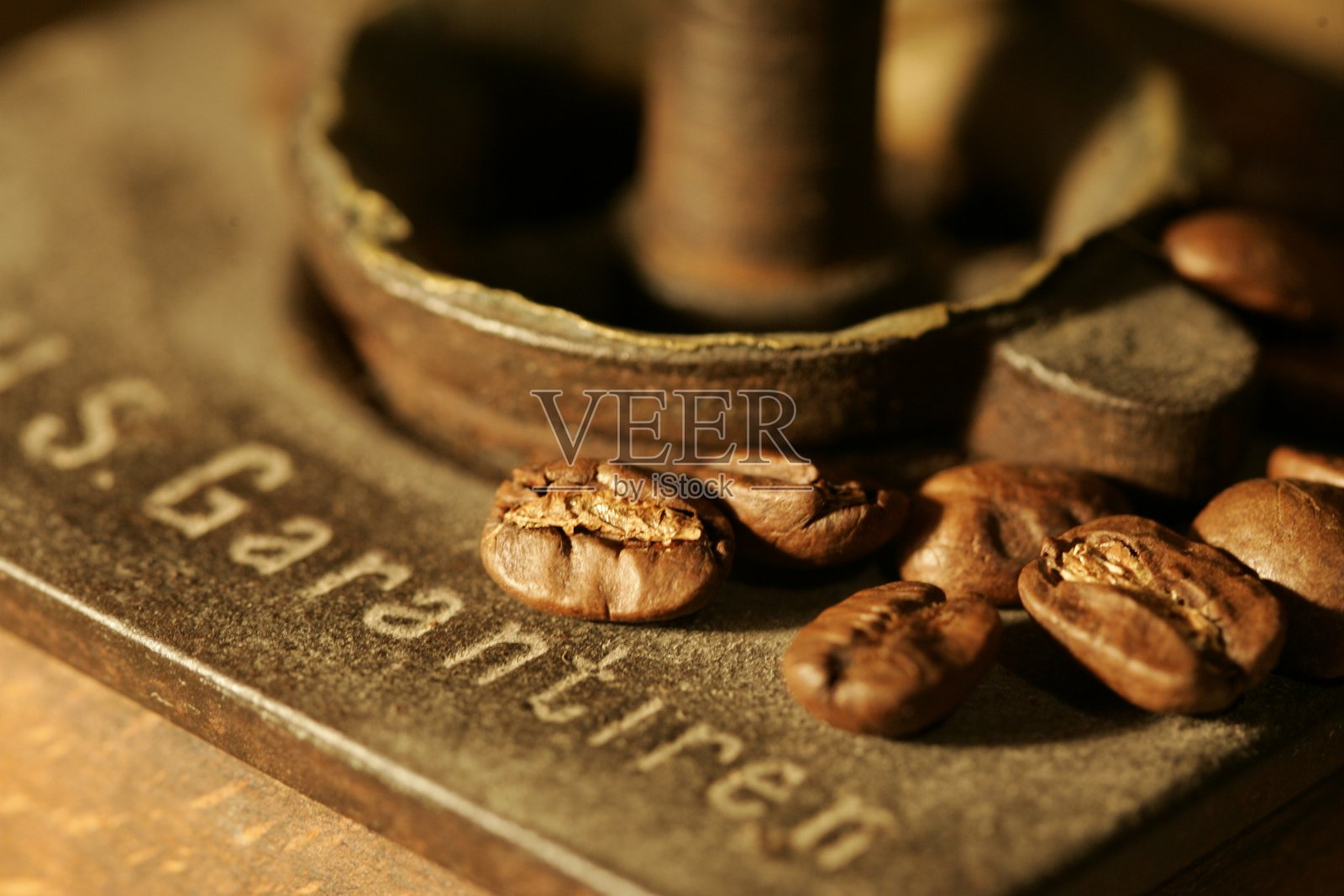 桌上放着咖啡豆和一个古老的木制研磨机，还有一个瓷杯、一个咖啡壶和一个水壶照片摄影图片