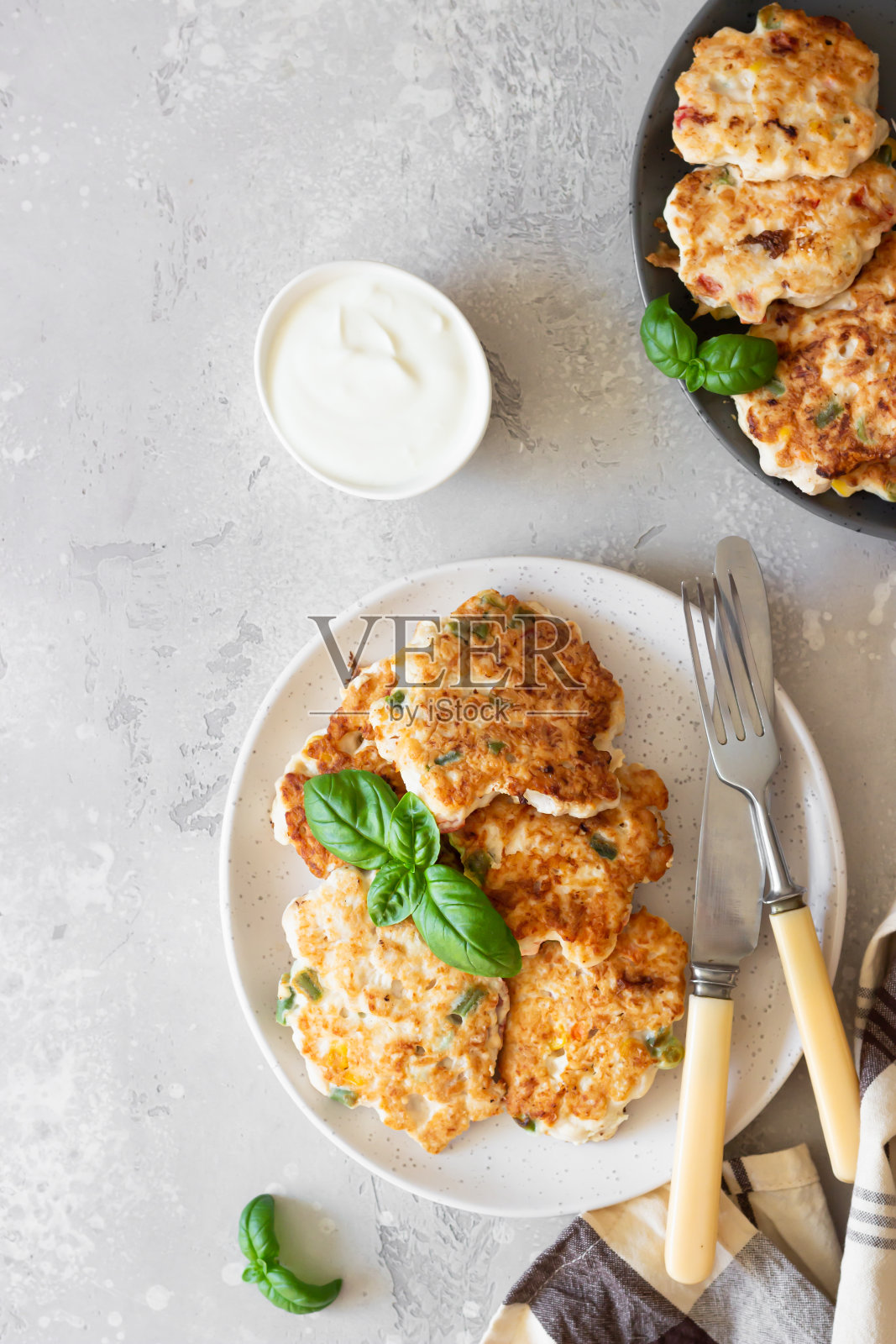 用玉米、青豆和红甜椒做的自制鸡肉片，浅灰色的石头桌。前视图。照片摄影图片