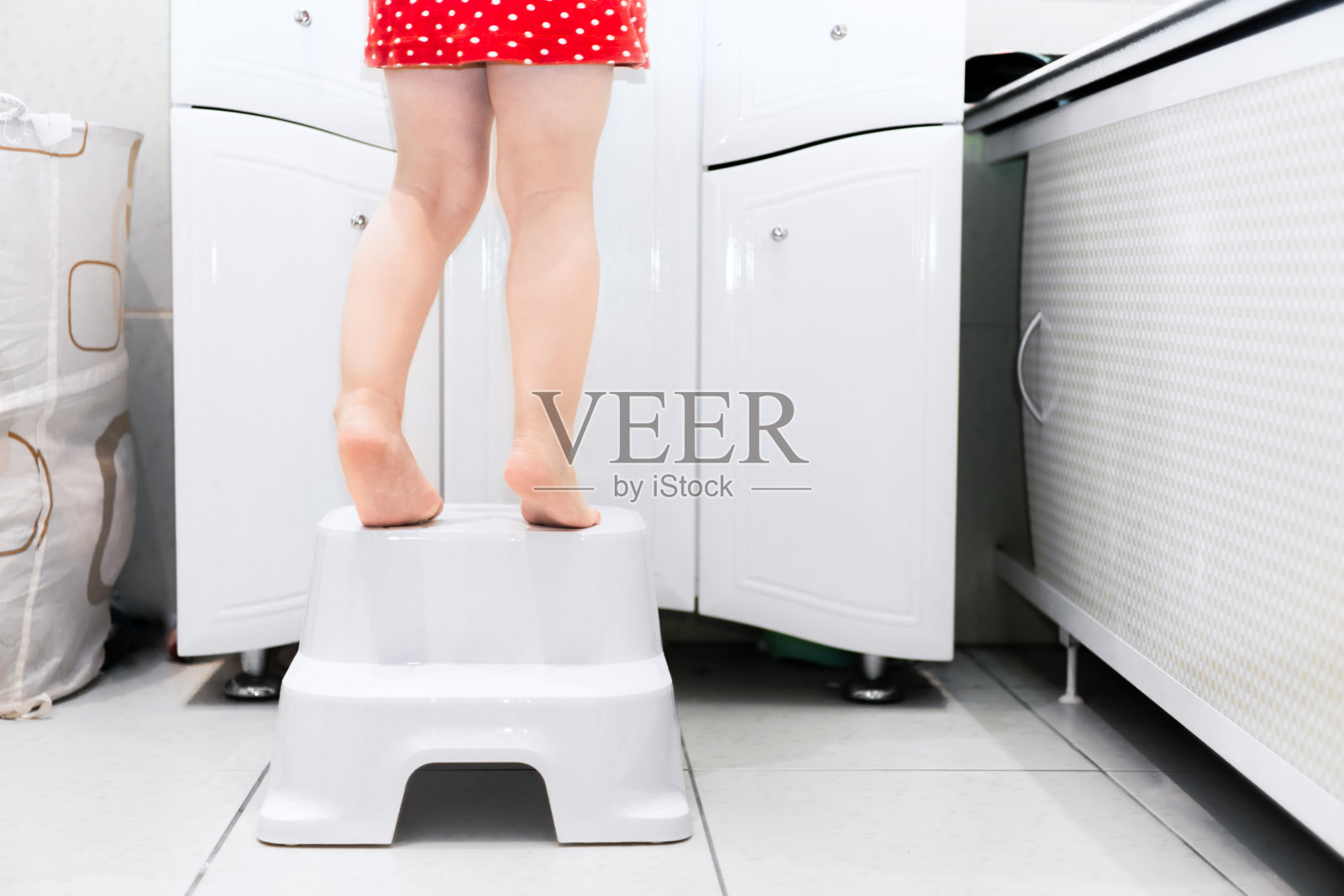 小女孩光着身子站在浴室的椅子上。儿童浴室水槽的高椅子支架照片摄影图片