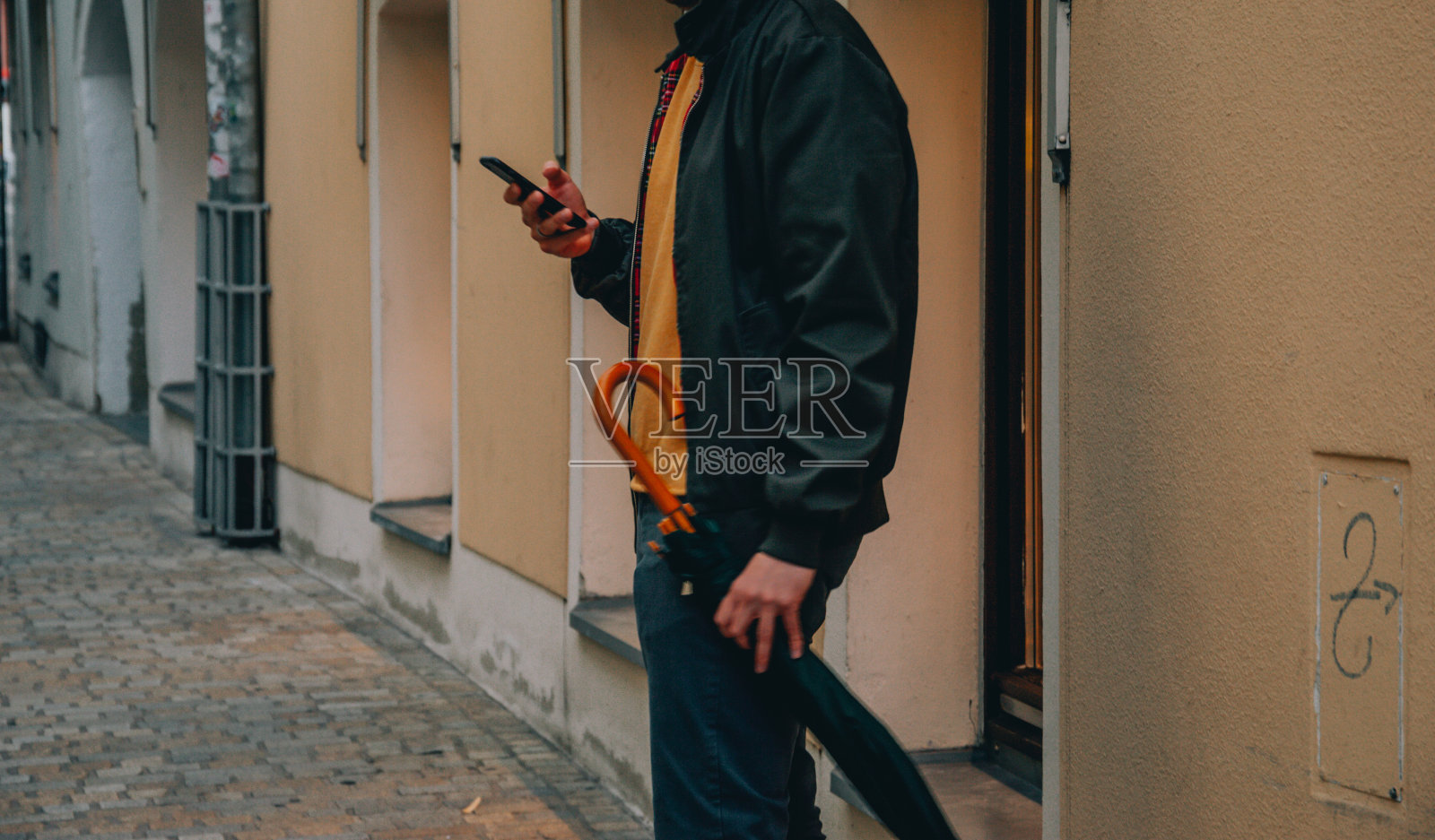 拿着手机和雨伞的男人照片摄影图片