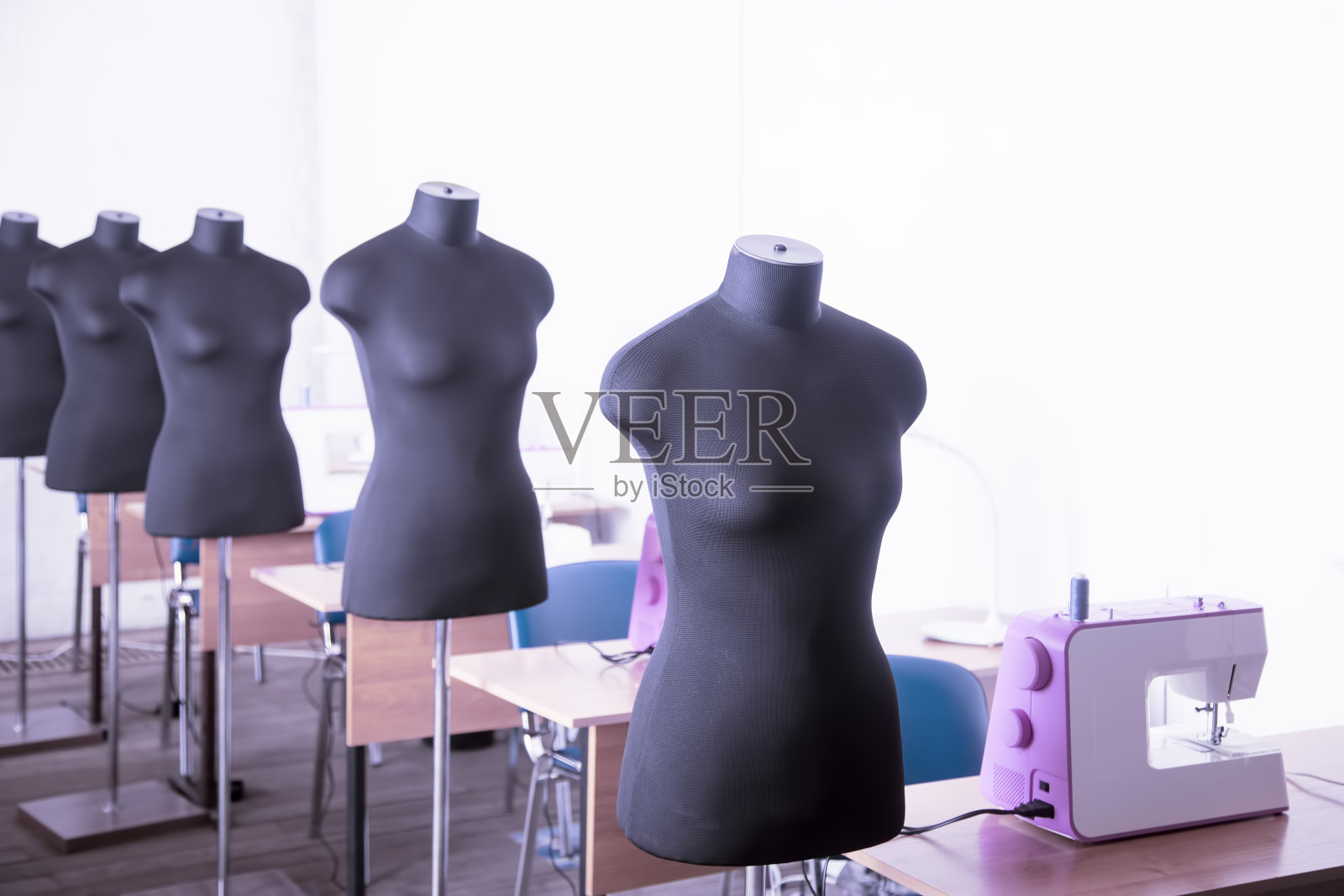 服装厂车间内部。用几台缝纫机关闭制作工作室。照片摄影图片