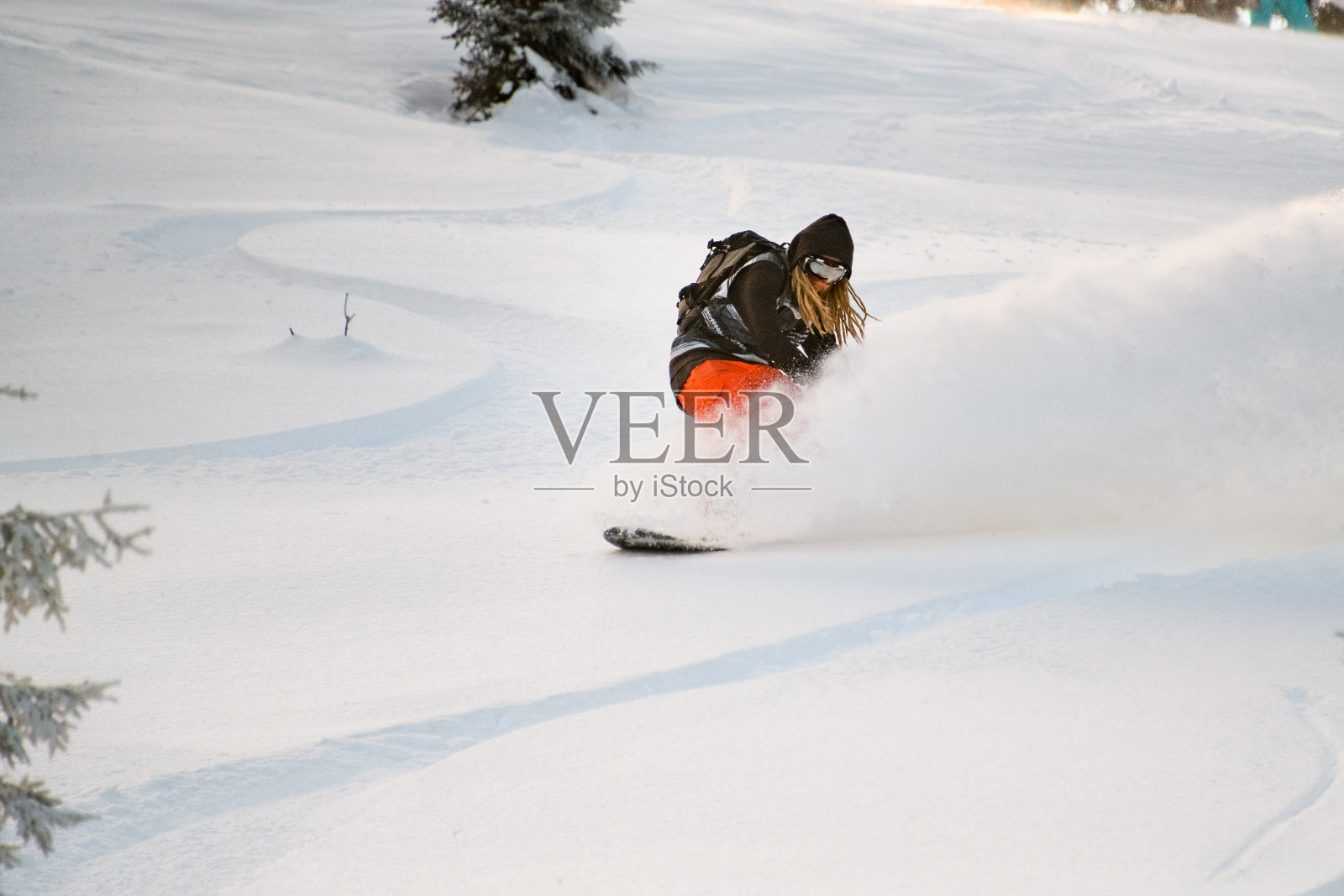 一个头上梳着雷鬼辫的家伙骑着滑雪板从山坡上滑下来照片摄影图片