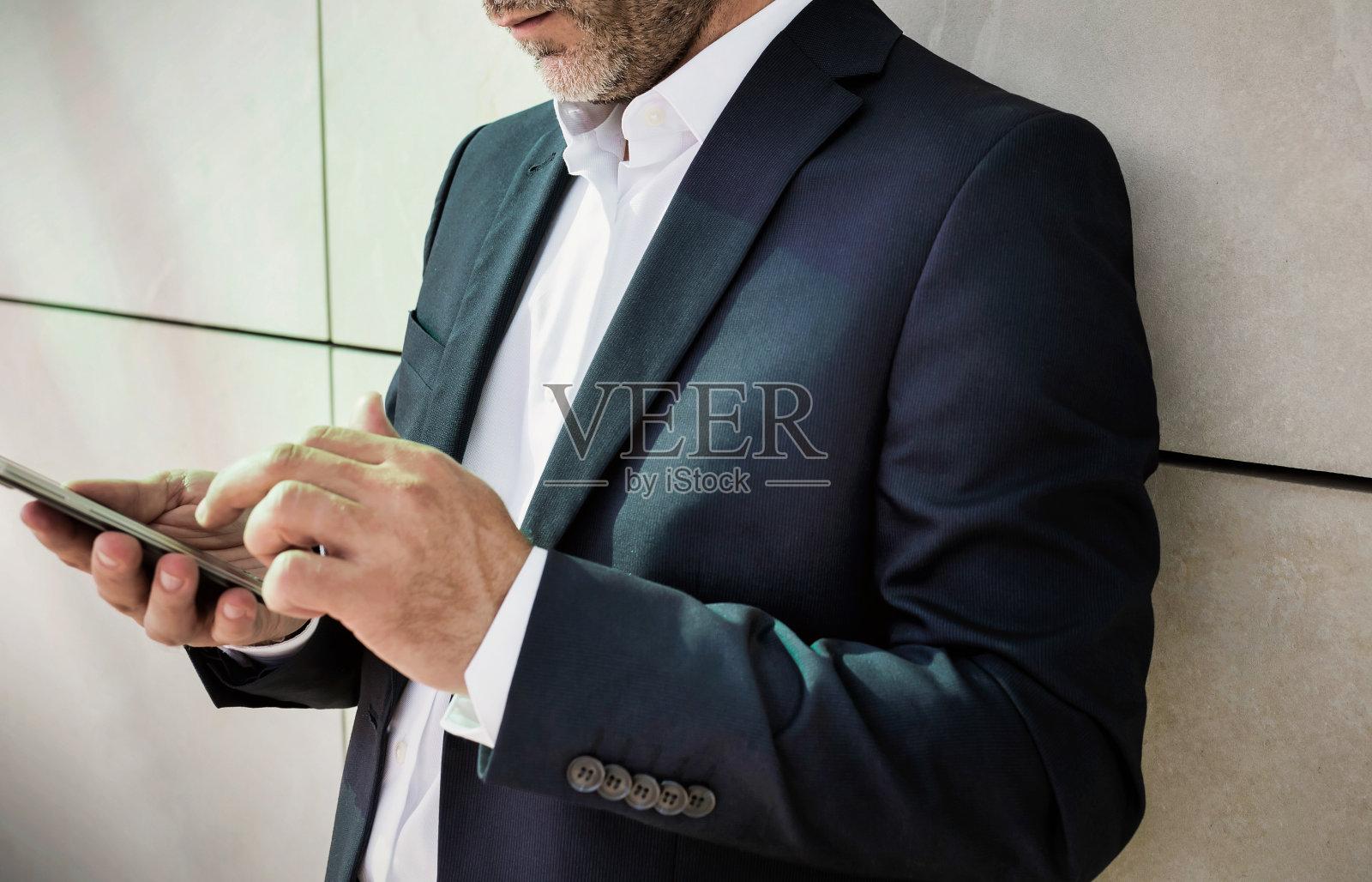 商人靠在墙上使用智能手机的肖像照片摄影图片