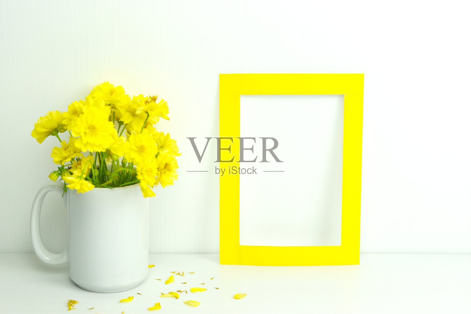 空白框与黄色花花瓶在白色背景。照片摄影图片