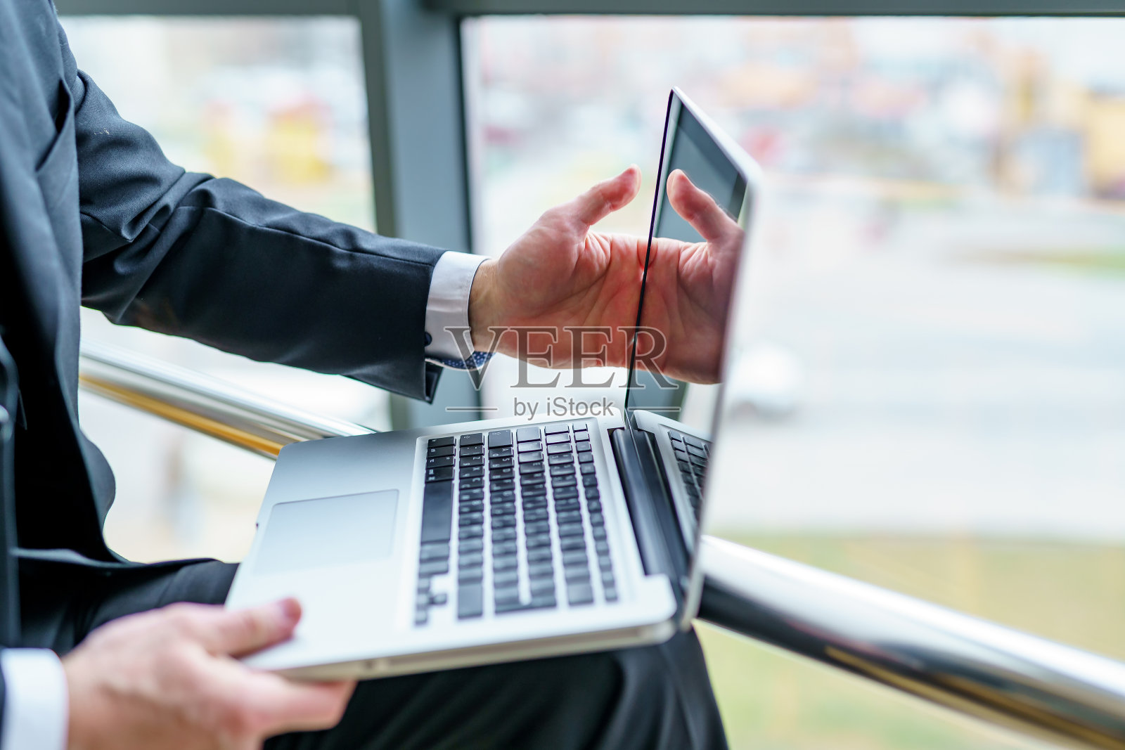 男人的手把笔记本放在膝盖上。照片摄影图片