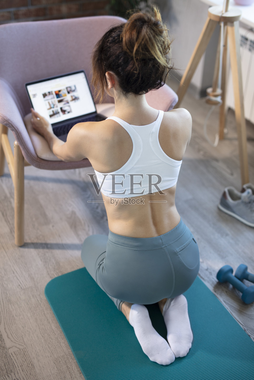 年轻苗条的女人在家训练。用笔记本电脑在网上锻炼。等待和准备训练。使用笔记本电脑。照片摄影图片