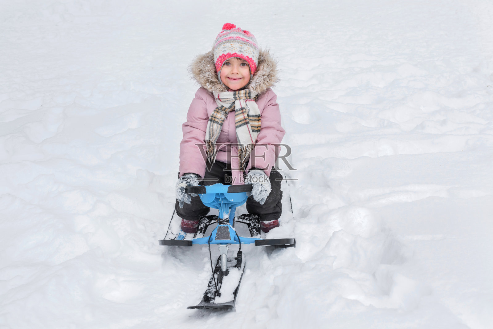 快乐的孩子在冬天骑着滑板车。金色的小时。照片摄影图片