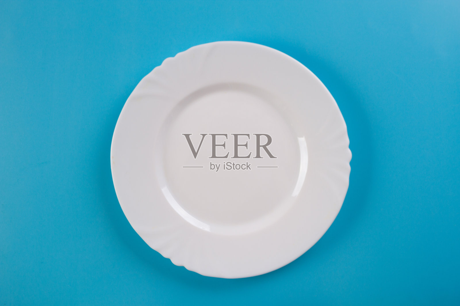 蓝色背景上的白色盘子照片摄影图片