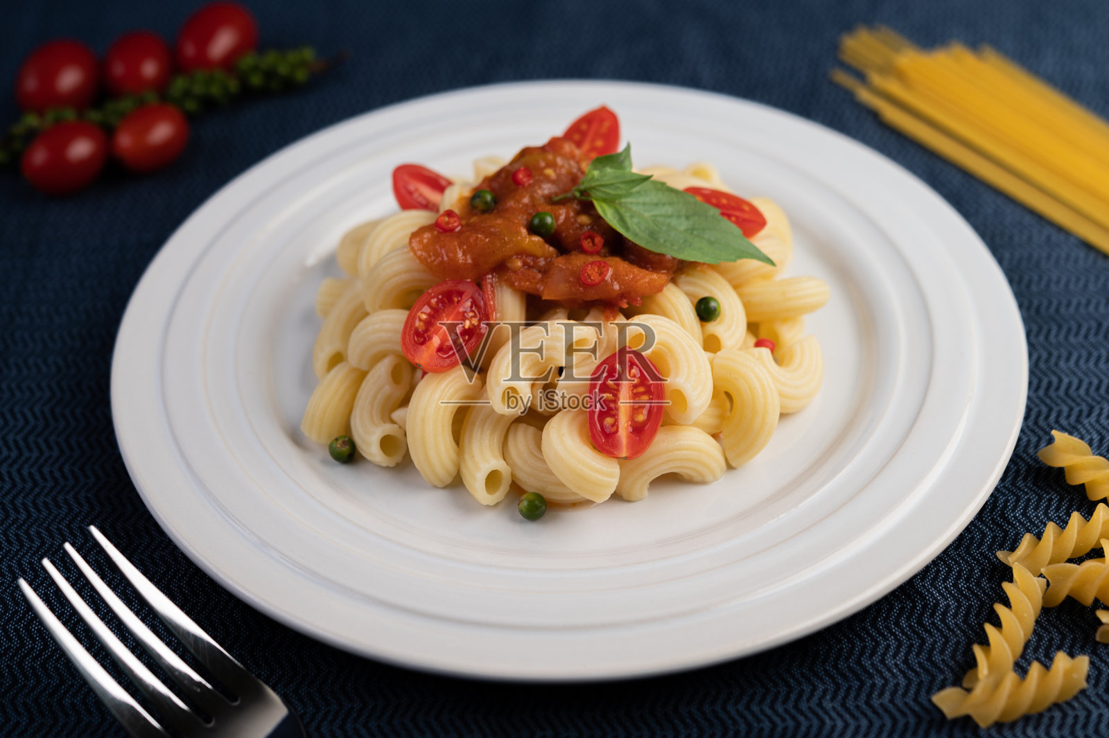 用番茄、辣椒、花椒籽和罗勒煸炒通心粉。照片摄影图片