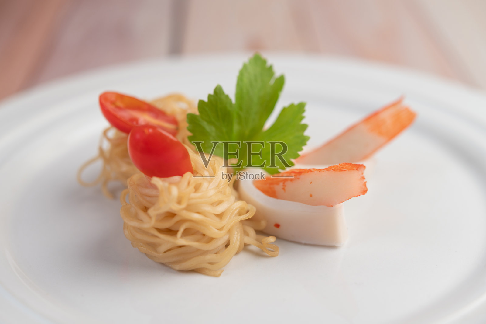 虾仁蟹炒方便面，配上番茄和辣椒，放在木地板上的白盘子里。照片摄影图片