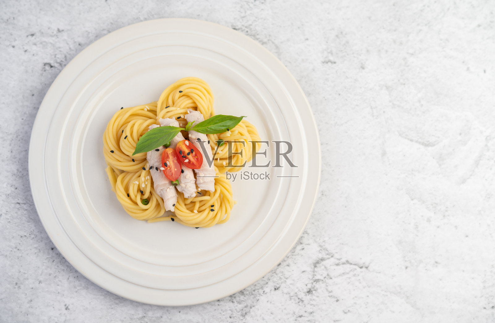 炒意大利面和猪肉，漂亮地排列在一个白色的盘子里。照片摄影图片