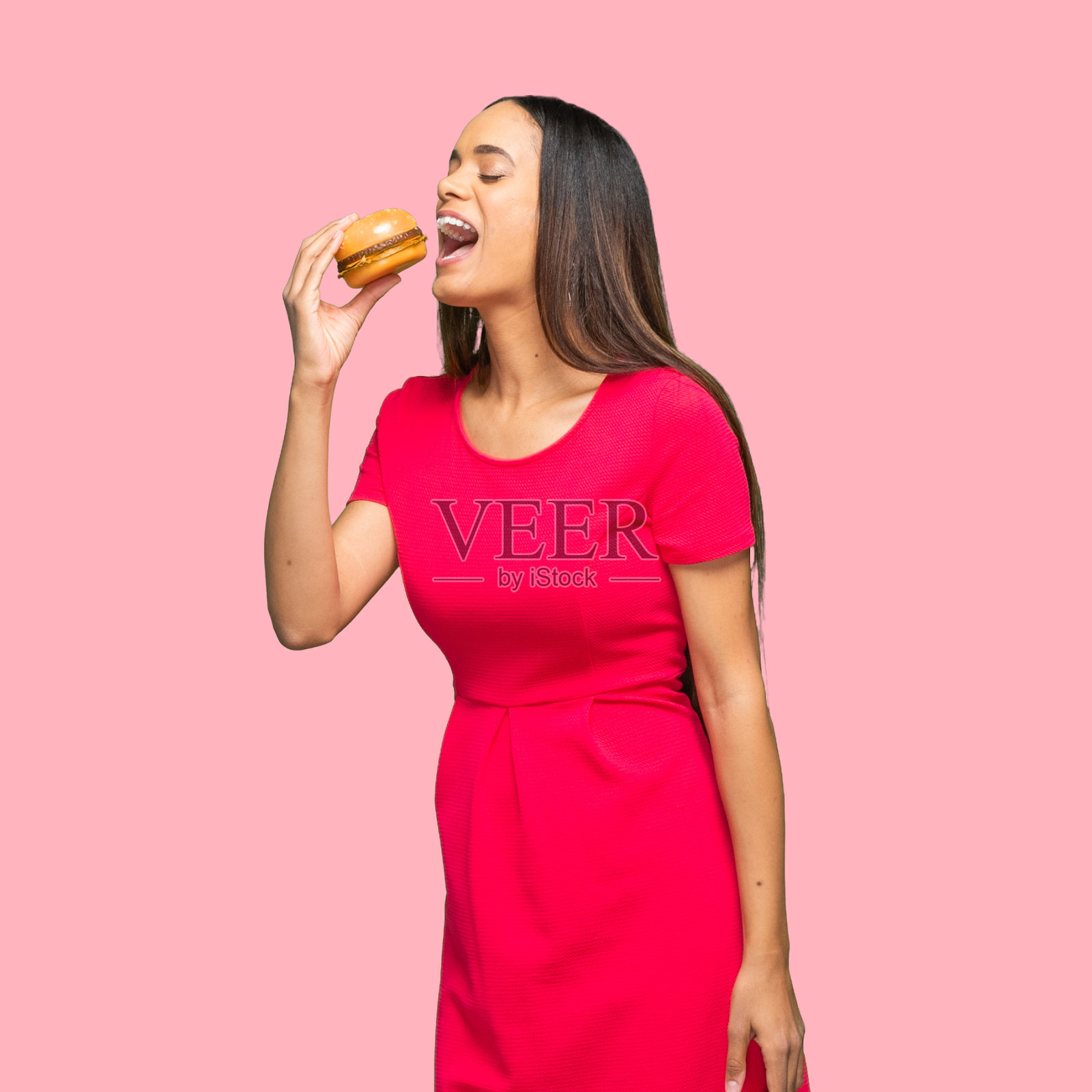 非裔美国女性穿着裙子，手拿小面包站在有色背景前照片摄影图片