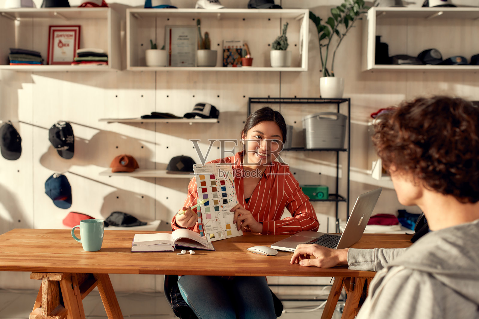 您创建的。我们打印。年轻女员工在办公室向男顾客展示颜色样品的肖像。女士在定制t恤，服装印刷公司工作照片摄影图片