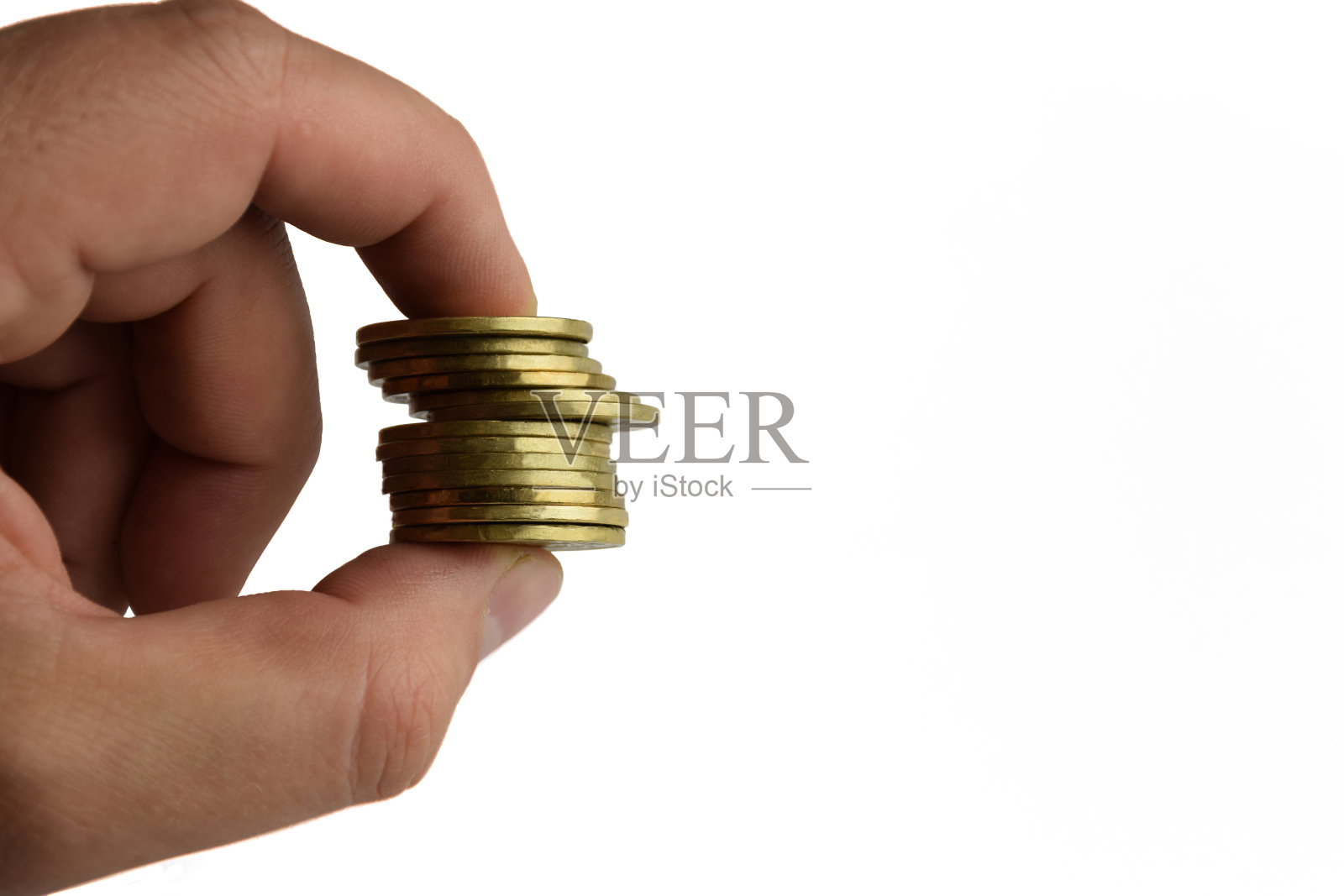 两根手指夹在白色背景上的一堆黄色的铁硬币照片摄影图片