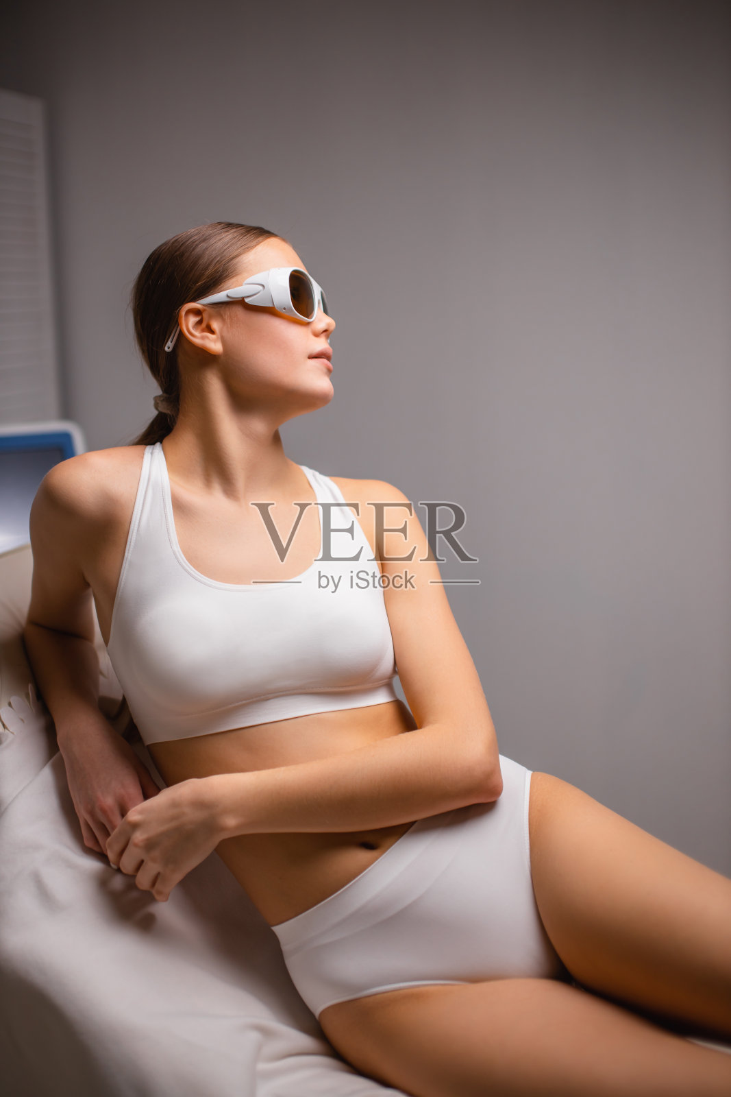 年轻的白人妇女坐在美容院，来接受脱毛程序照片摄影图片