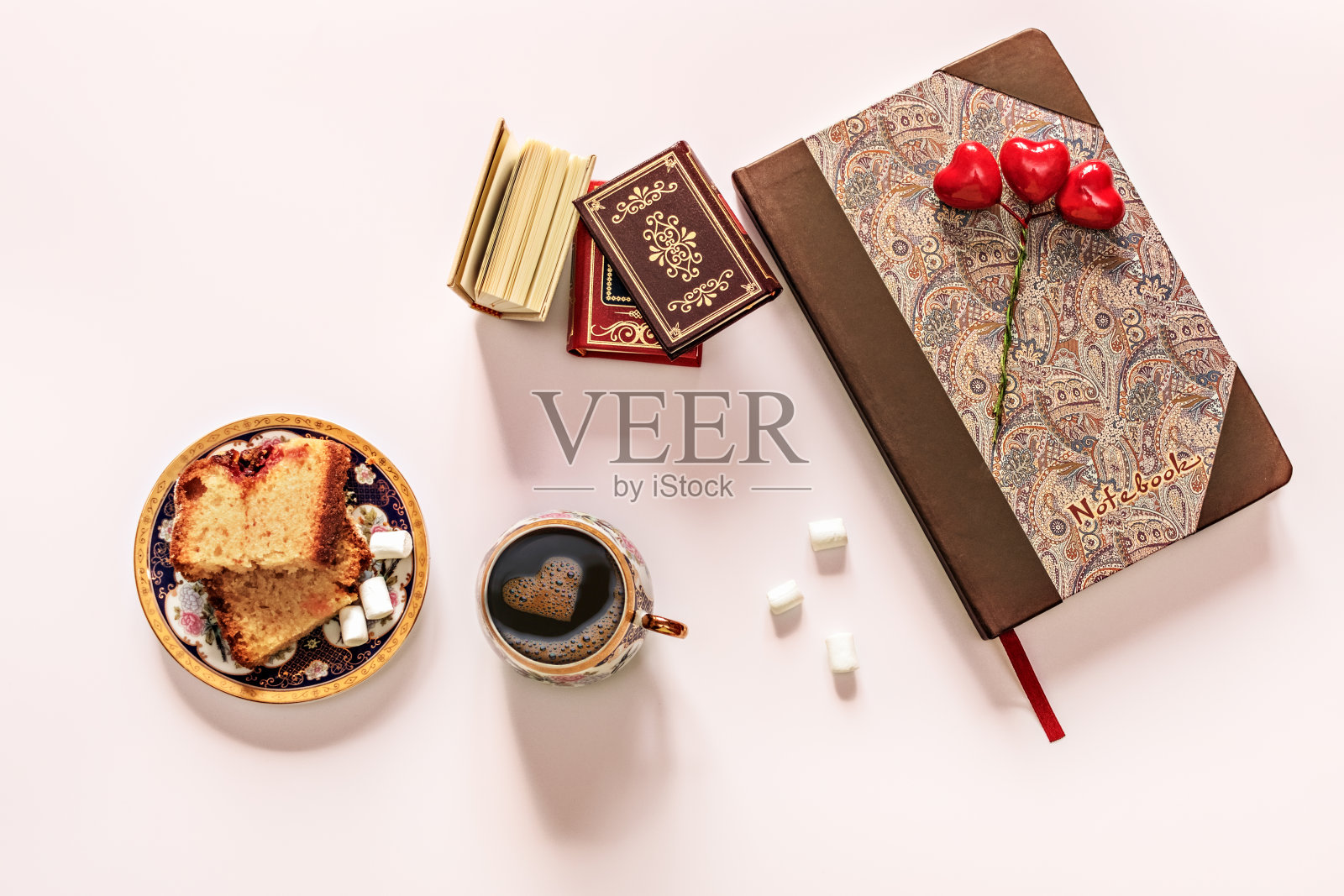 桌子上有书，纸杯蛋糕，棉花糖是一杯黑咖啡和泡沫心形。照片摄影图片