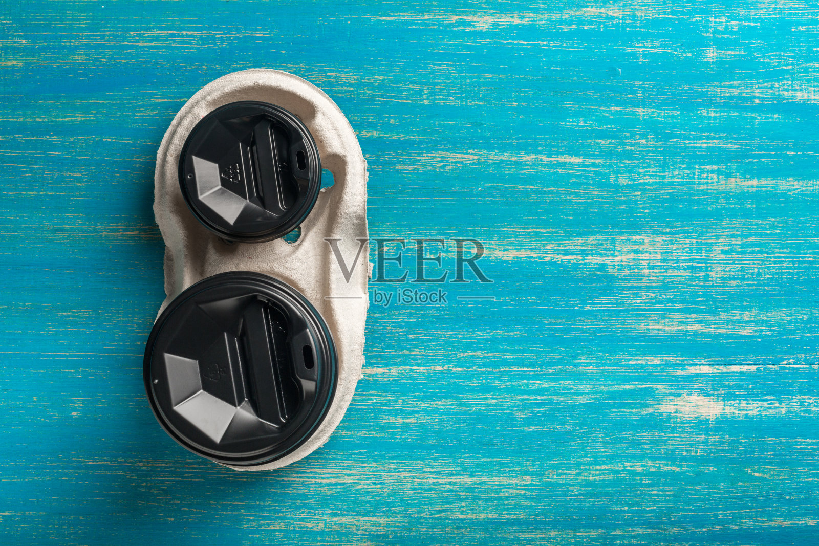 蓝色木质背景上的两个一次性纸杯咖啡和一个一次性杯架。照片摄影图片