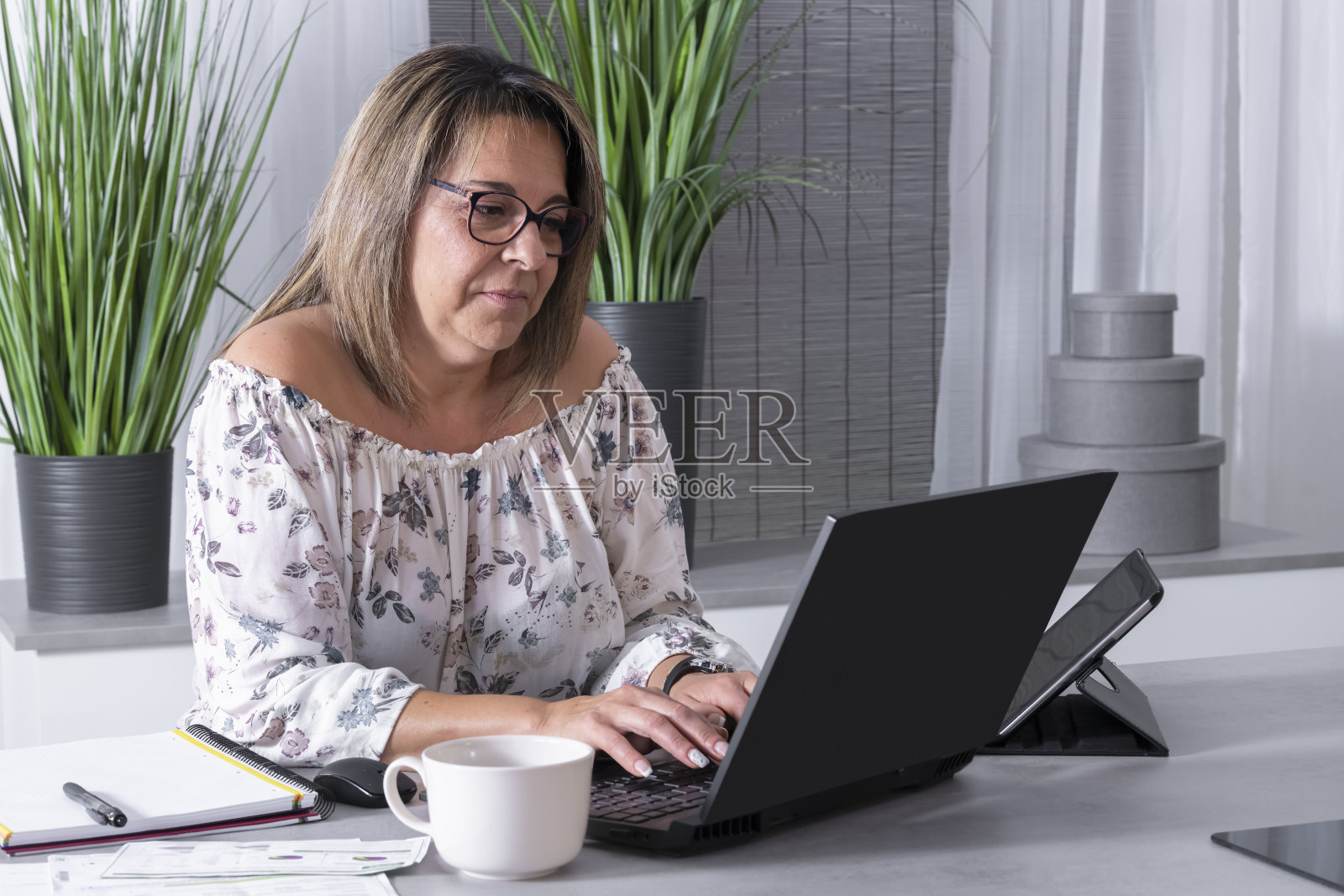 一个在笔记本电脑前工作的成熟女人身边都是笔记本照片摄影图片