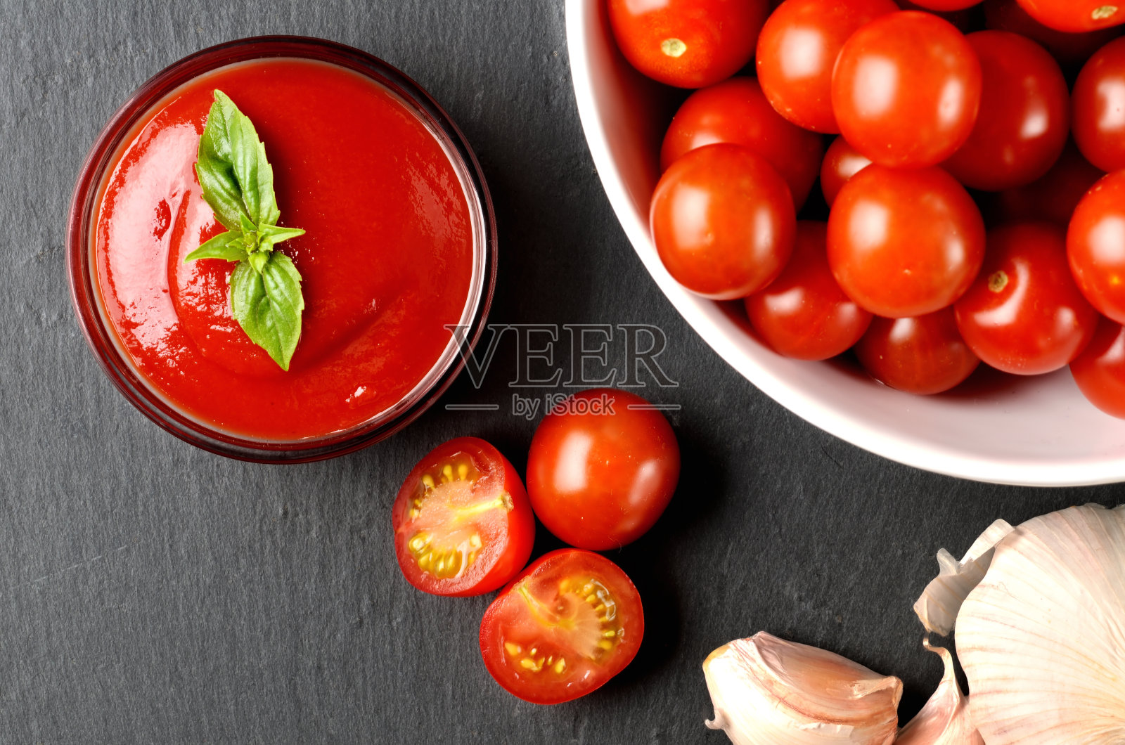 特写自制番茄酱，由新鲜的樱桃番茄，大蒜，罗勒在黑色石板盘子。照片摄影图片