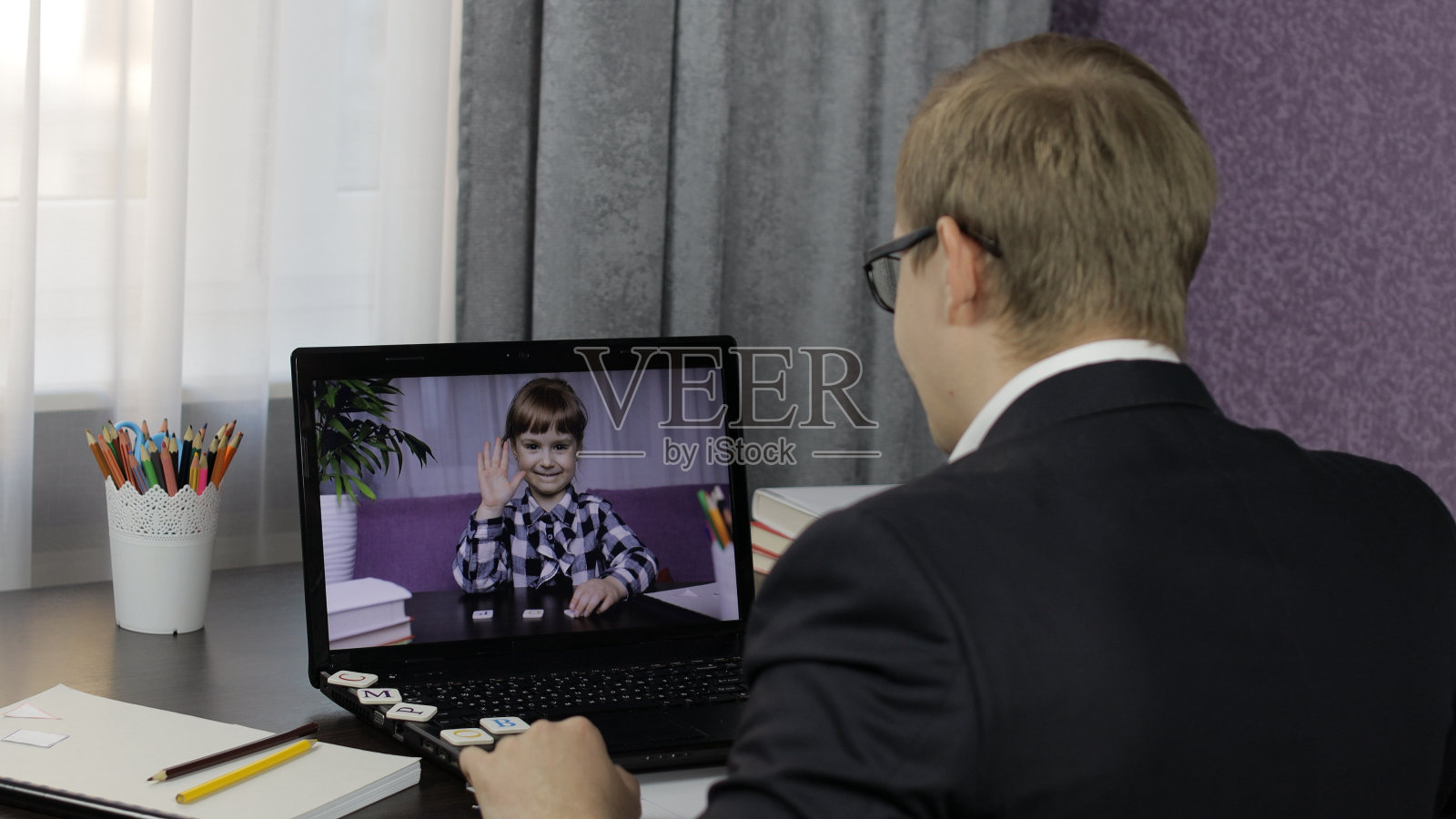 男老师在电脑上和小学生视频通话。远程教育照片摄影图片