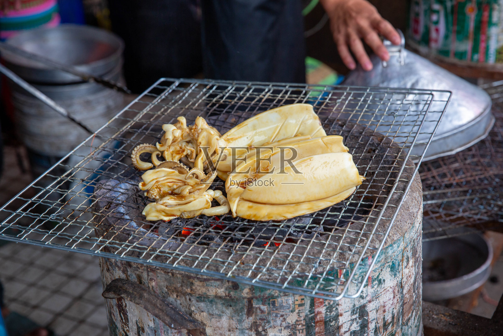炭炉上烤墨鱼。烤鱿鱼很好吃。可以在泰国街头找到。烧烤烧烤热木炭。照片摄影图片