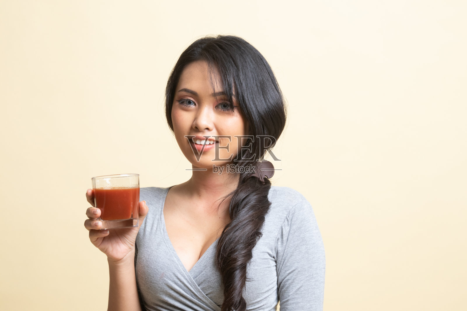 年轻的亚洲女子喝番茄汁。照片摄影图片