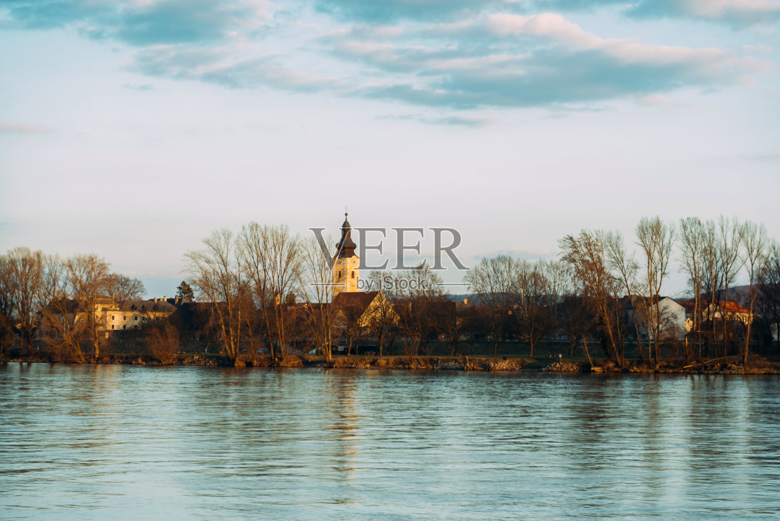 沐浴在阳光下的小村庄，横跨奥地利的河流。照片摄影图片