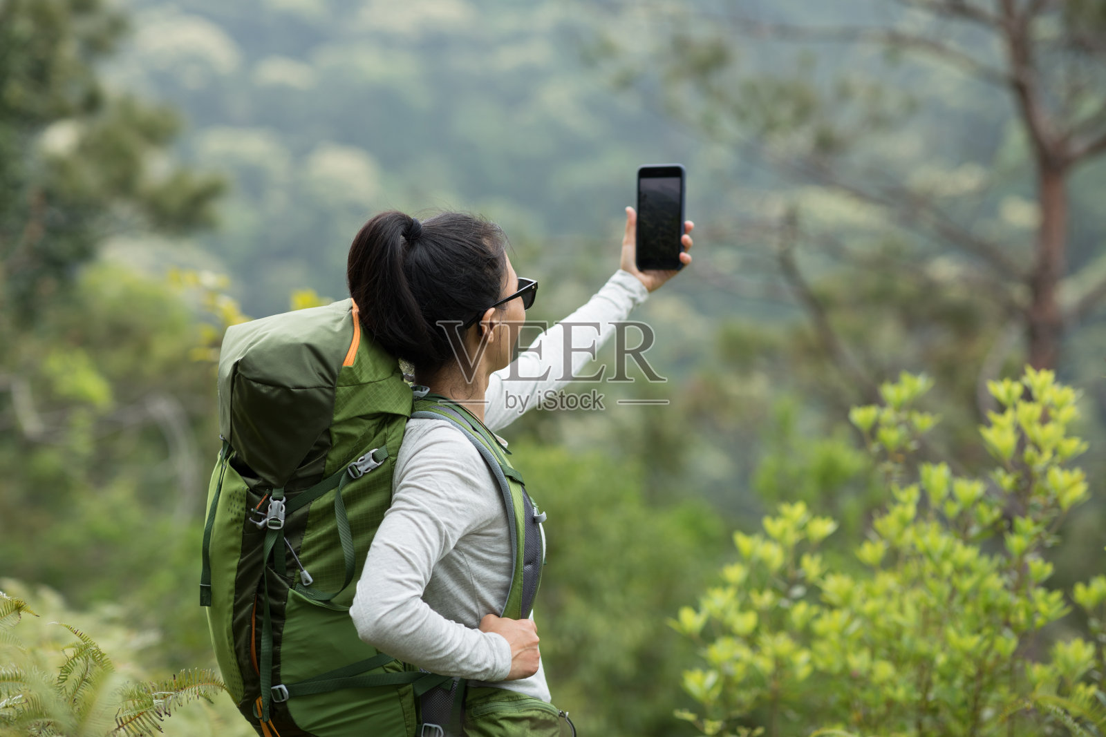女性徒步旅行者使用智能手机在春天的山拍照照片摄影图片
