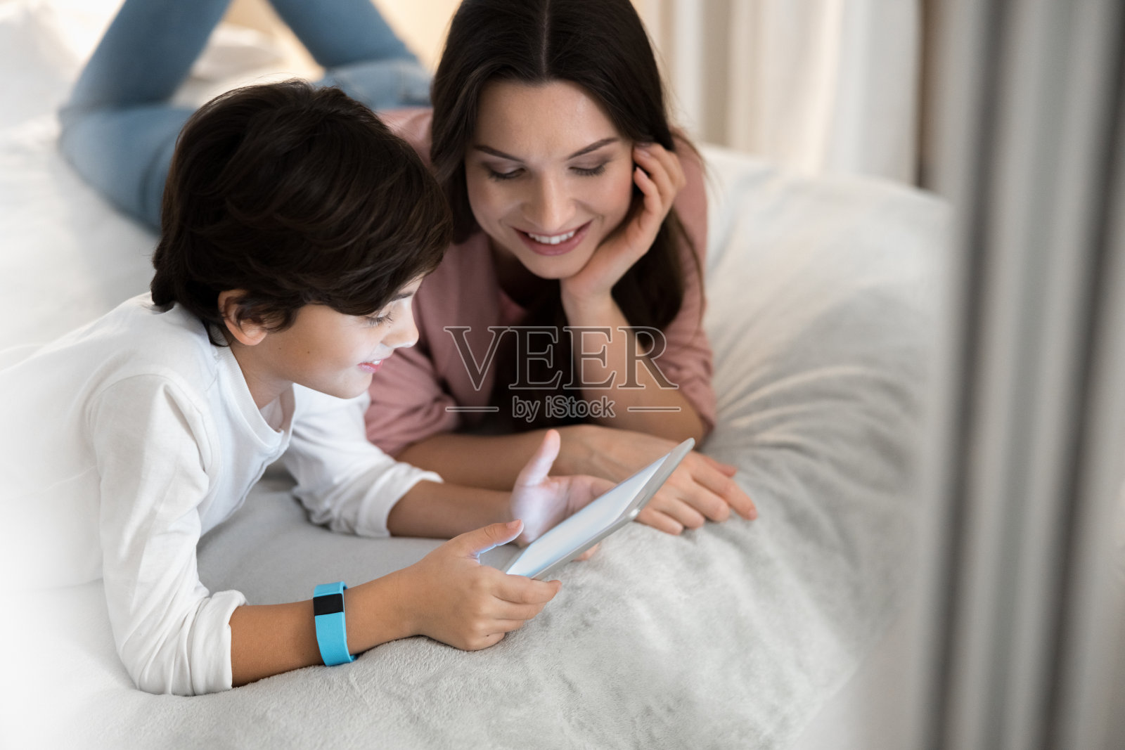 床上躺着一个拿着药片的男孩照片摄影图片